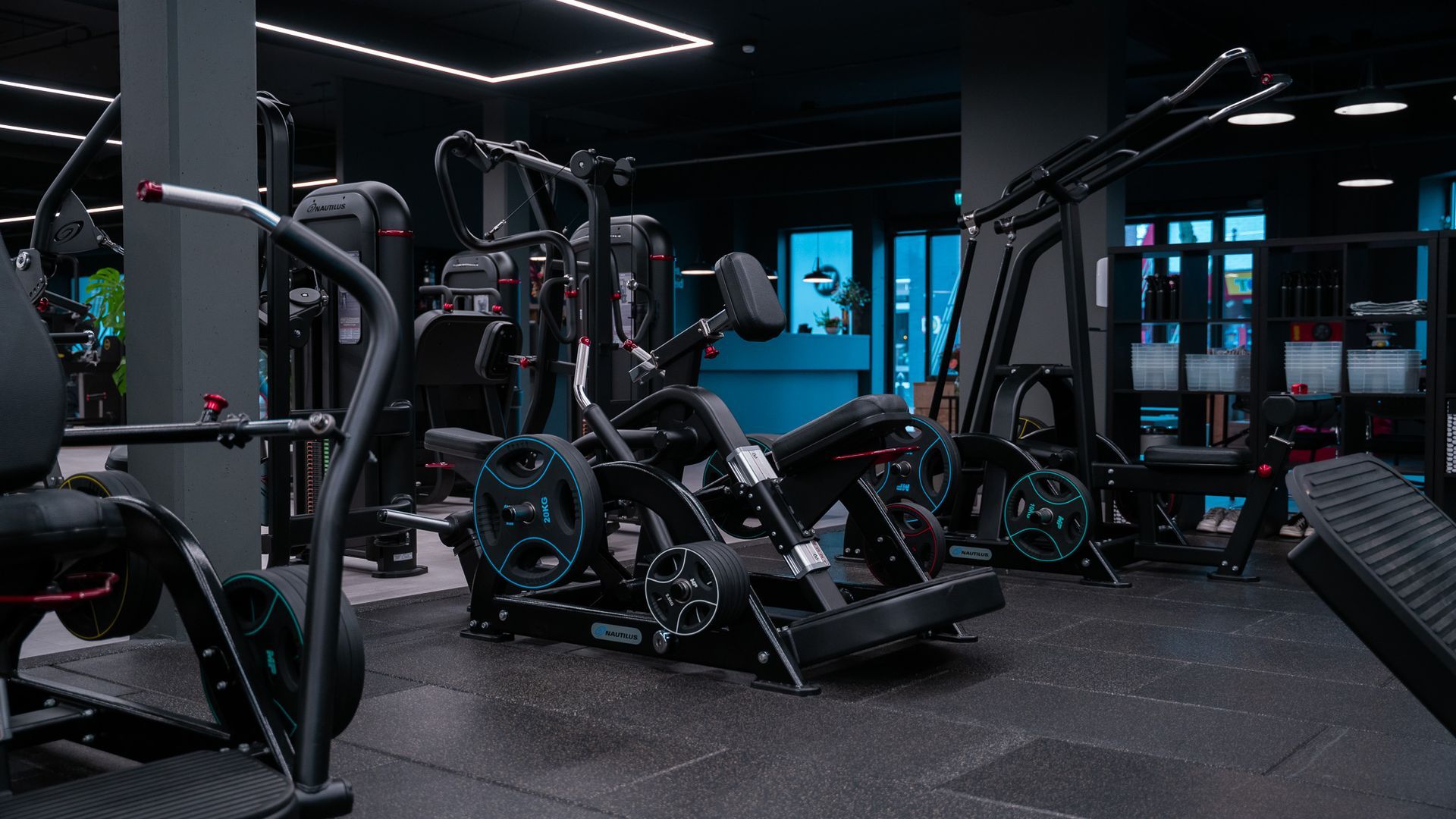 Interieur van een sportschool met gewichtsapparaten. Zwarte apparatuur op een zwarte vloer, donkere omgeving.