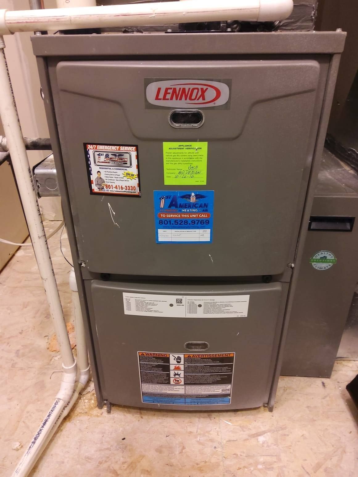 Lennox furnace unit in a utility room, gray metal cabinet with warning labels and ductwork above.