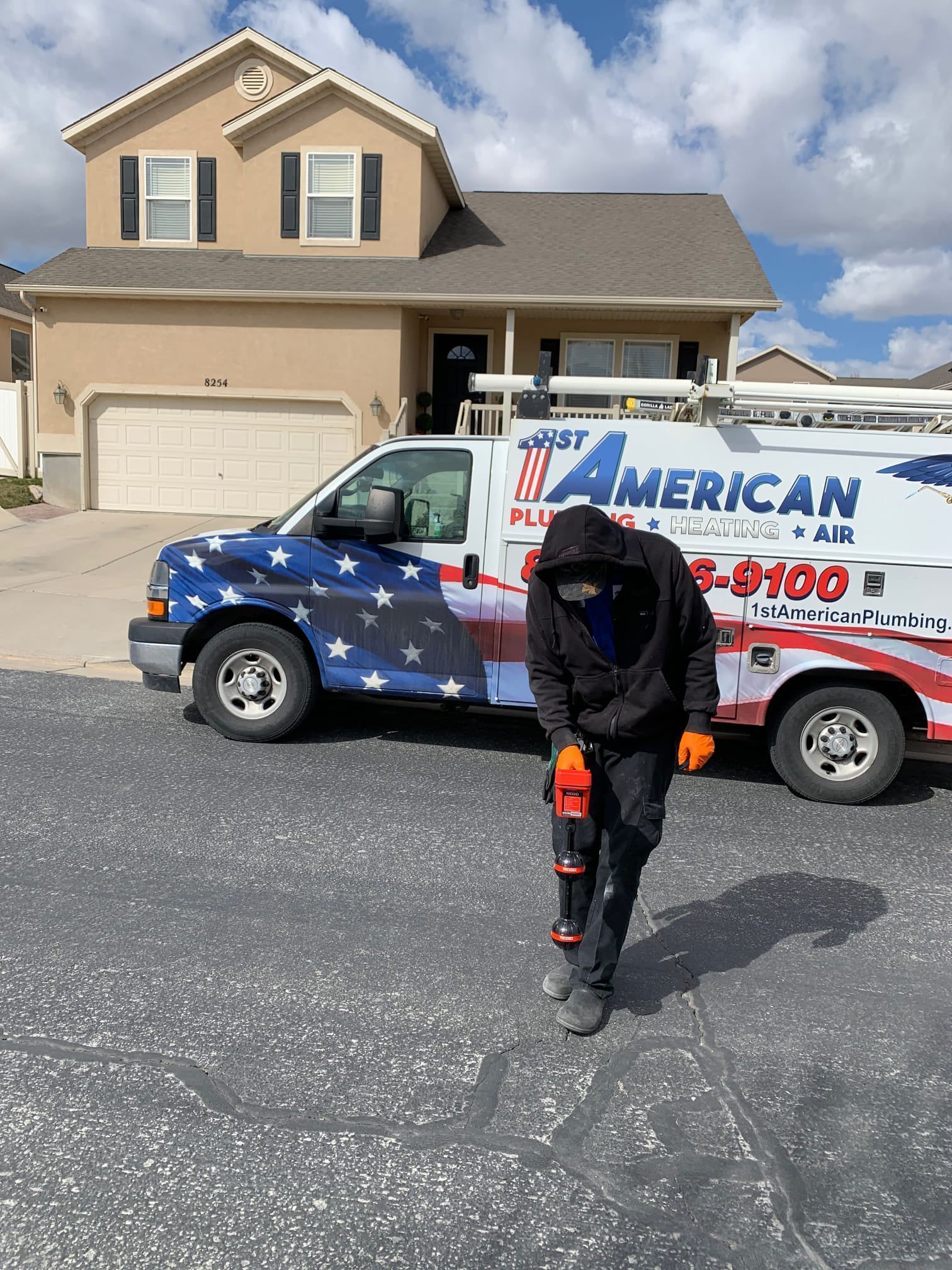 Worker in black uniform walking toward a star-spangled American roofing truck in a suburban driveway.