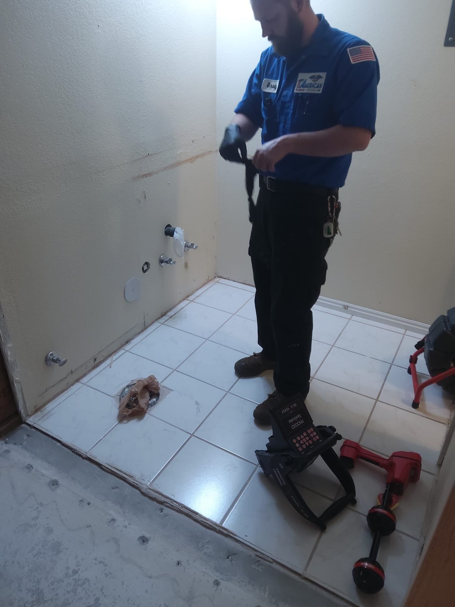 Technician standing on tile floor beside inspection equipment and tools in a small room