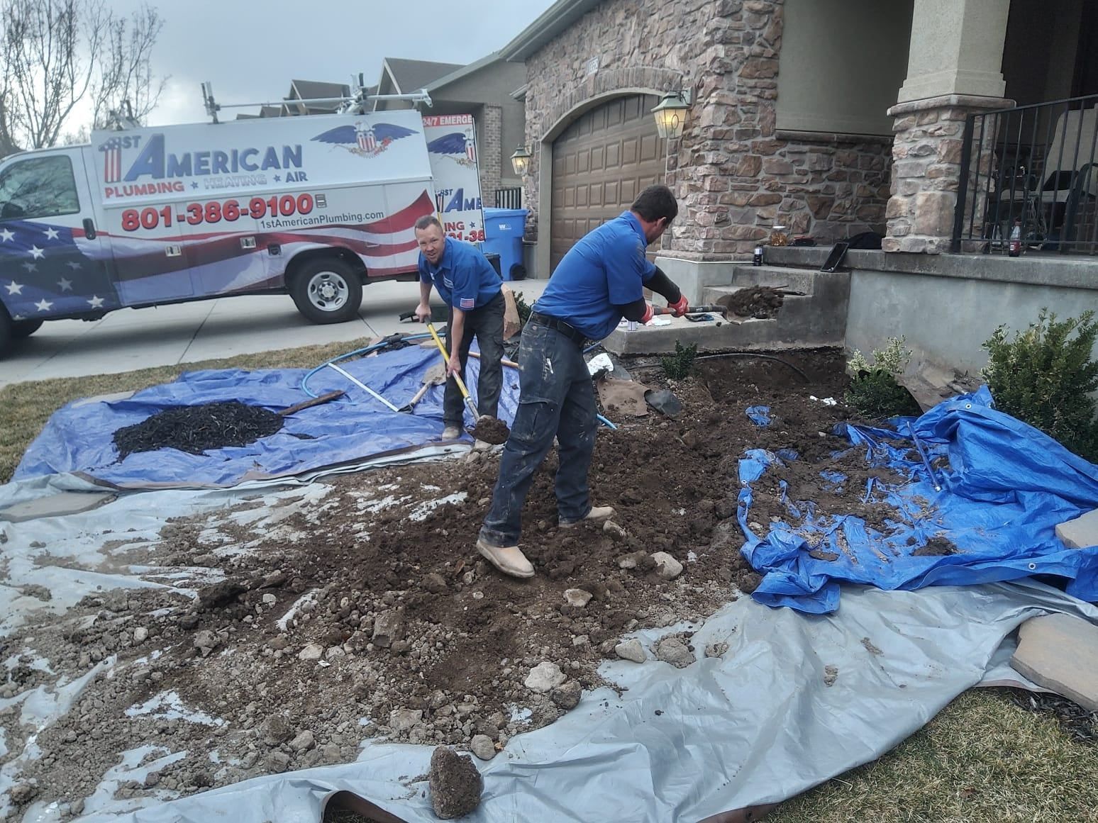 Workers shoveling dirt on a tarp beside a house, with a service van parked nearby