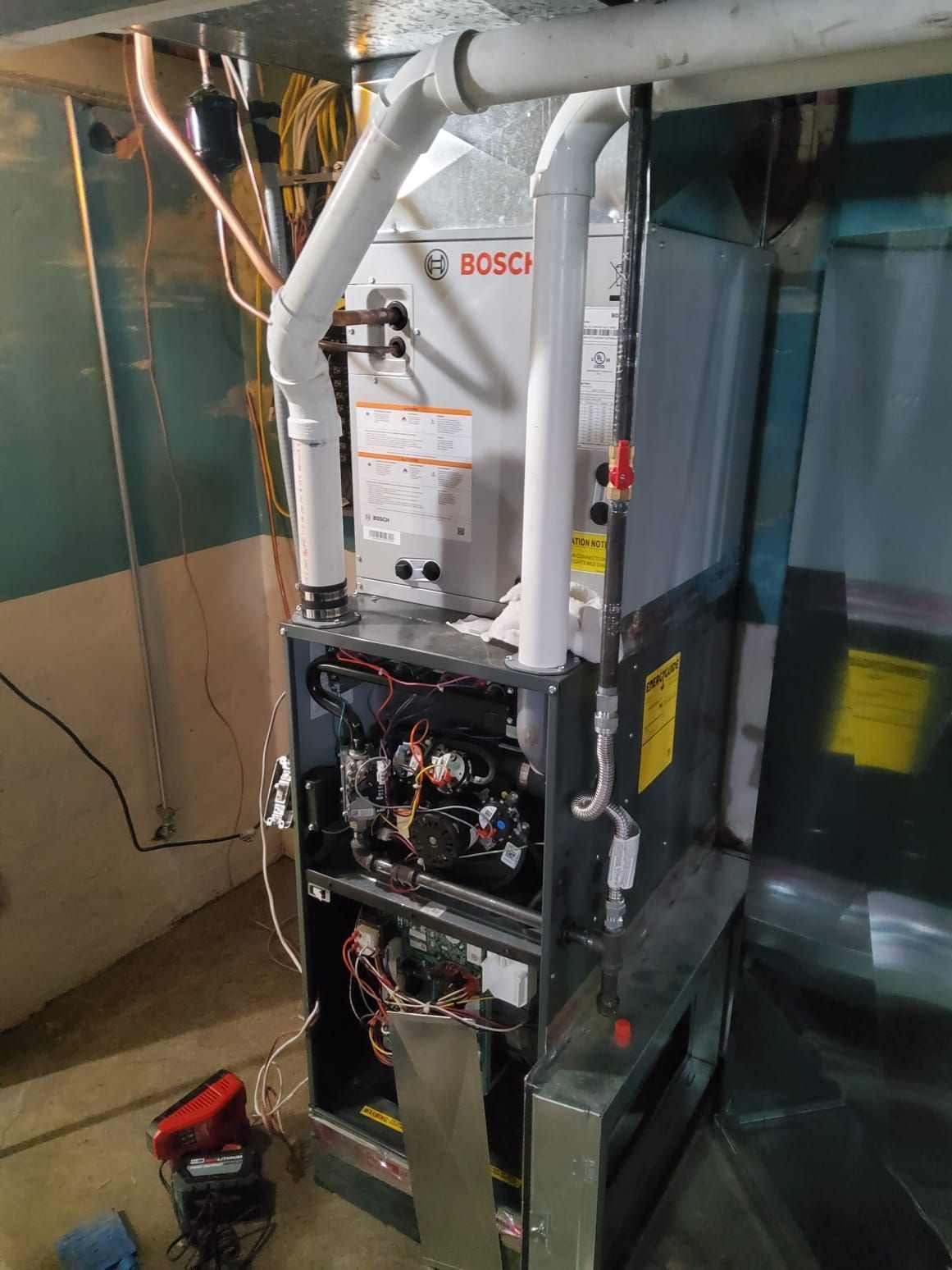 Open furnace in utility room, showing Bosch HVAC components and exposed wiring.