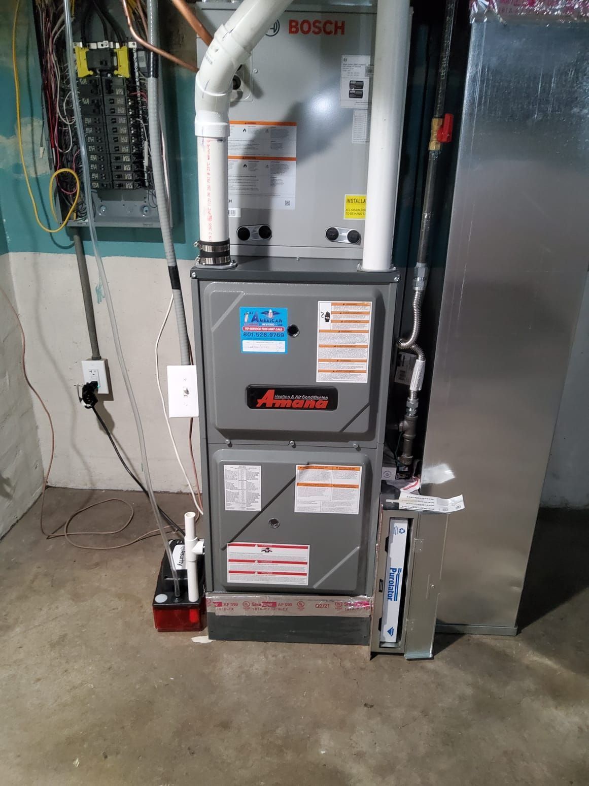 Furnace and water heater in a utility room, with pipes, wiring, and concrete floor.