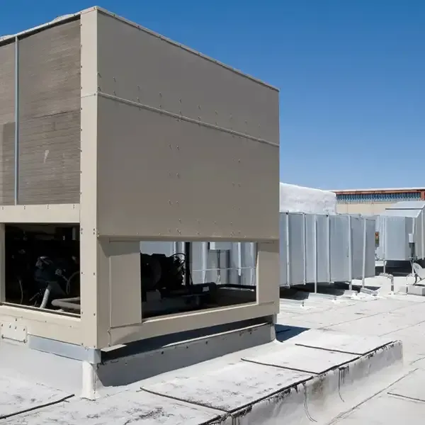 Rooftop view of large HVAC units and beige utility buildings under a clear blue sky.