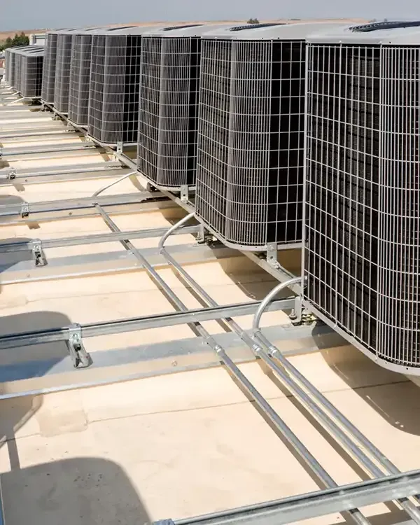 Rows of rooftop HVAC units with metal grates and ducts on a flat roof