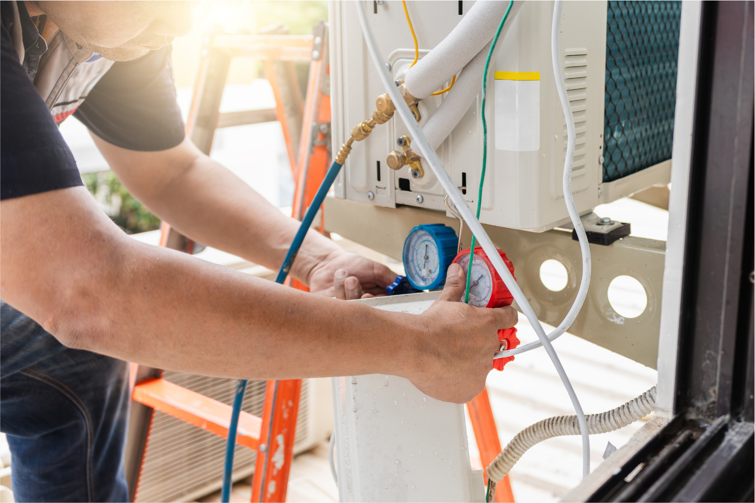 Technician connecting gauges to outdoor HVAC unit during maintenance