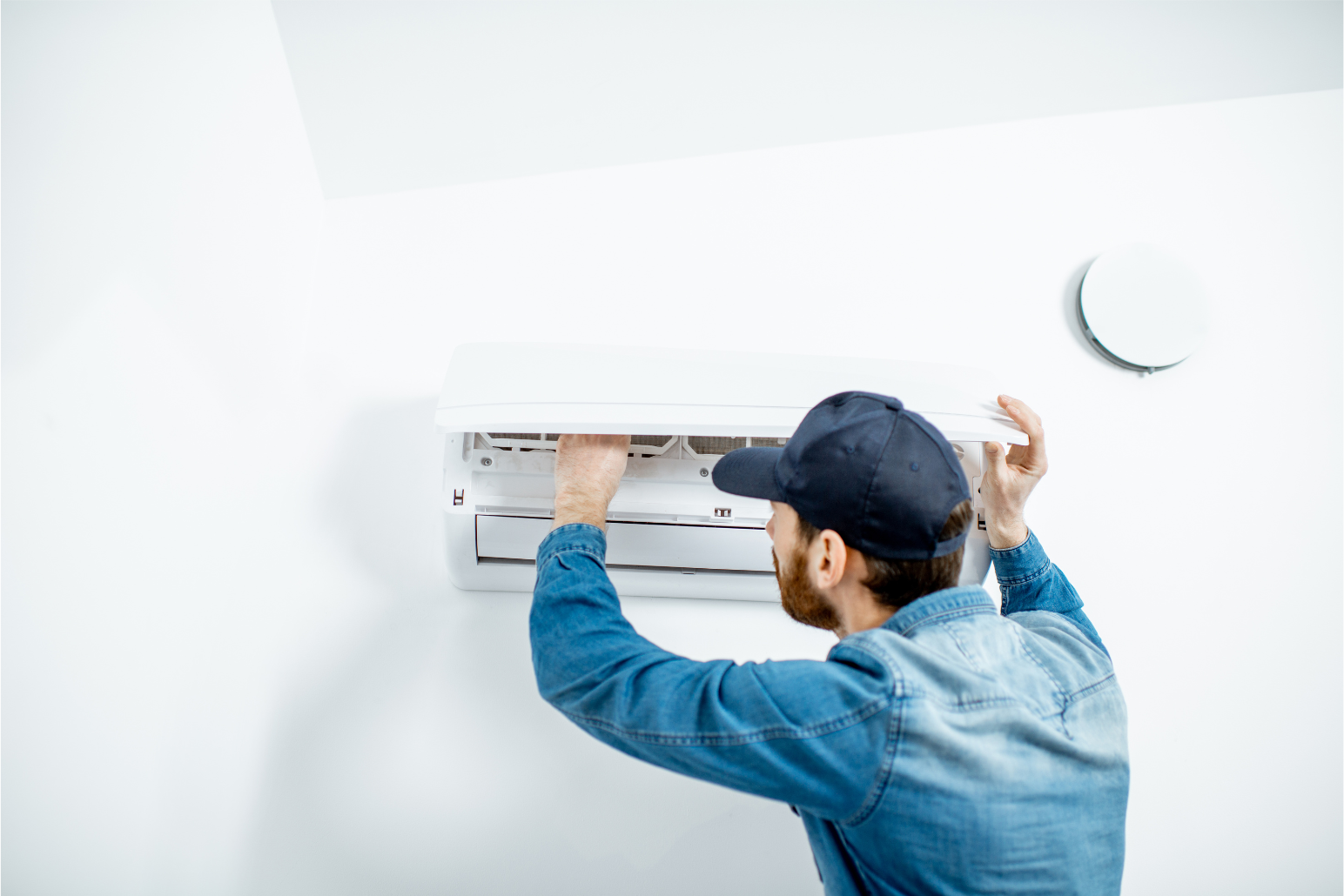 Technician installing a wall-mounted air conditioner in a bright room