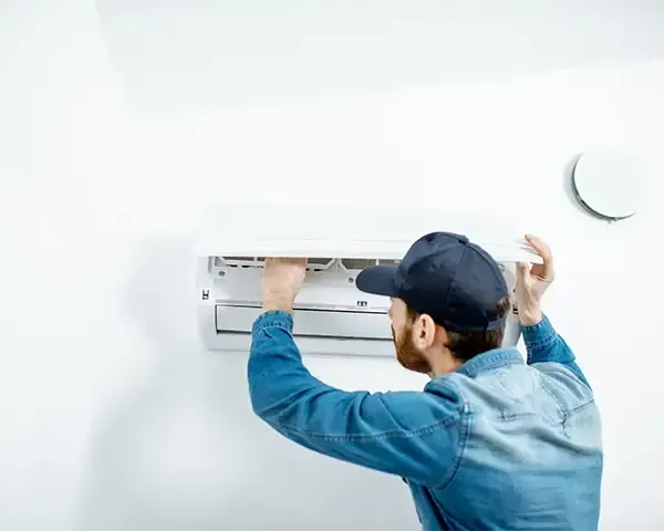 Technician installing a wall-mounted air conditioner in a bright room