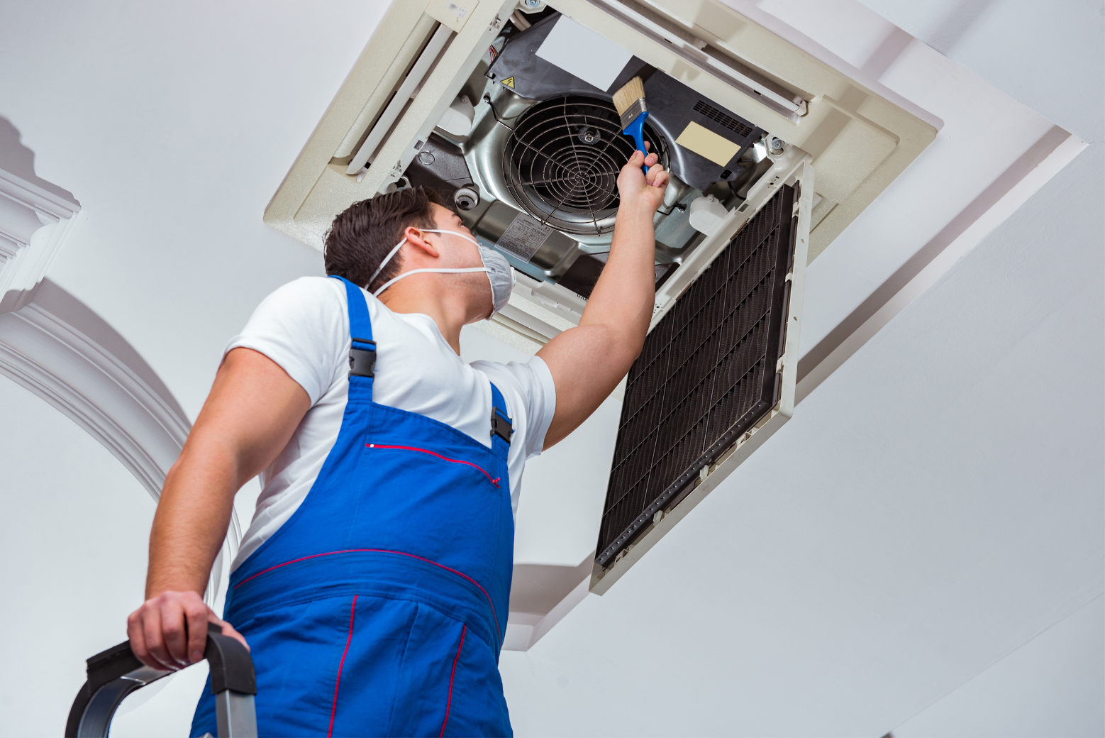 HVAC technician working on an outdoor air conditioning unit next to a wooden wall.