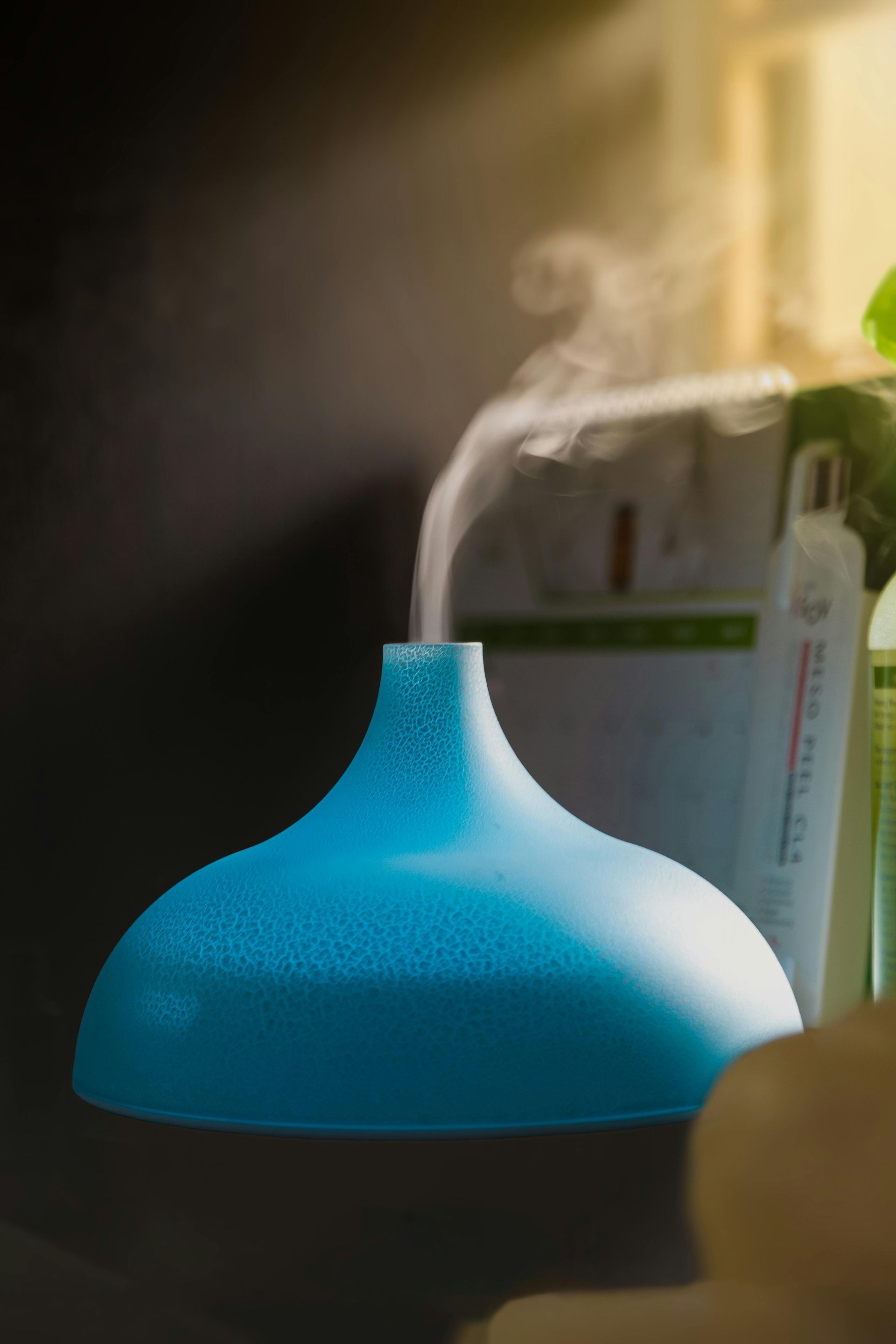 Blue vase on a desk beside a blurred smartphone in the background