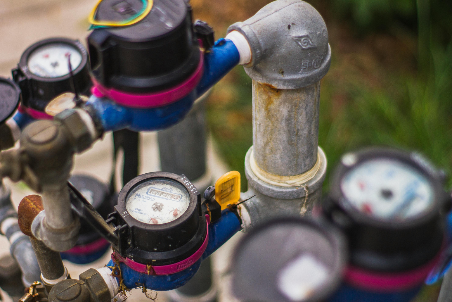 Water meters and blue pipes with valves in an outdoor utility setup