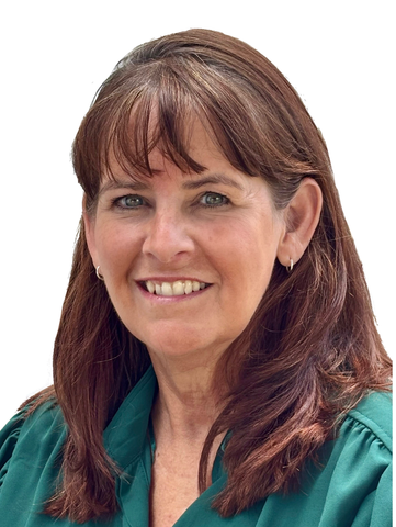 A woman in a grey sweater is smiling in front of a white wall.