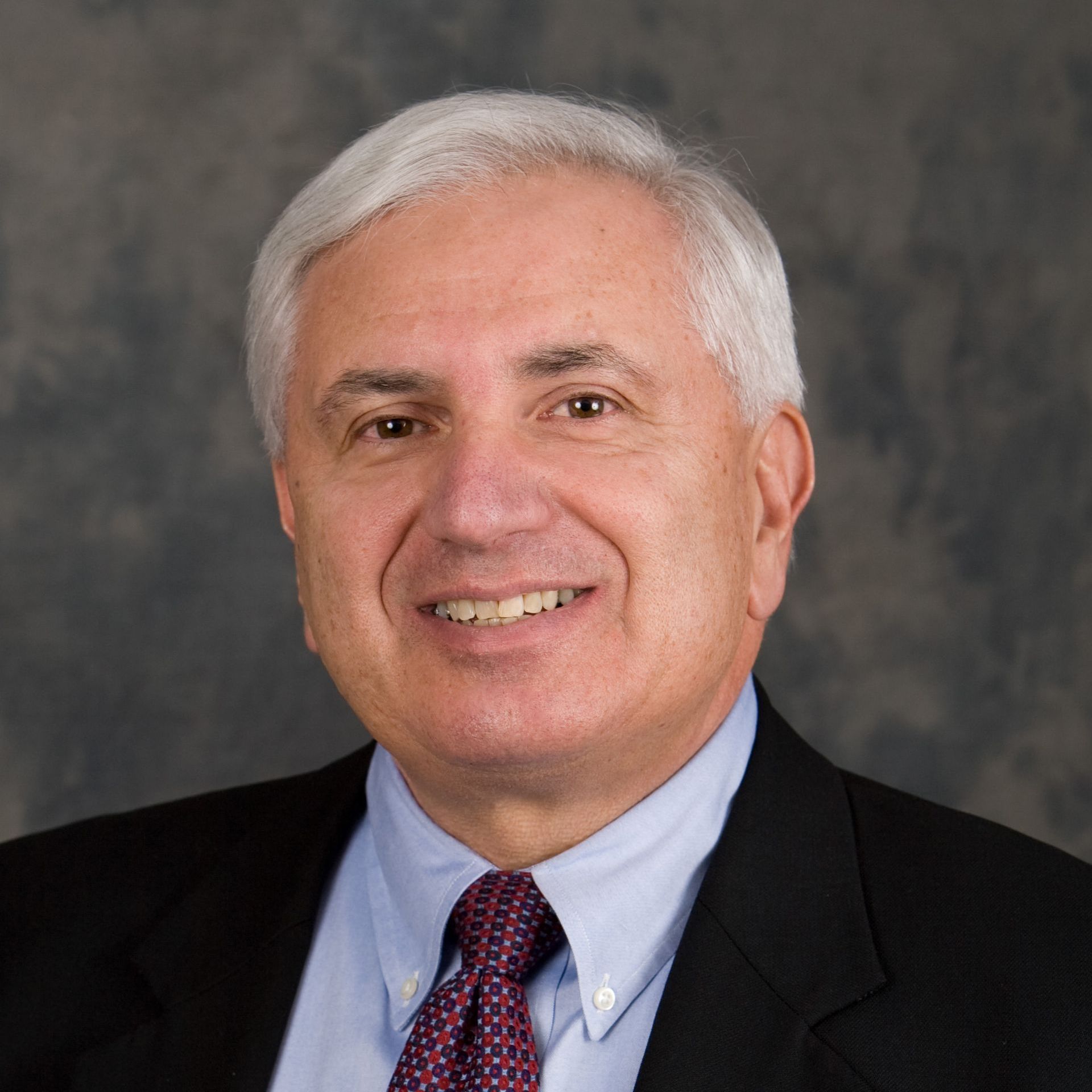A man in a suit and tie is smiling for the camera