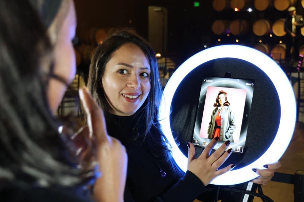 A person smiles while using a digital interface mounted inside a glowing circular ring light in a dimly lit venue.