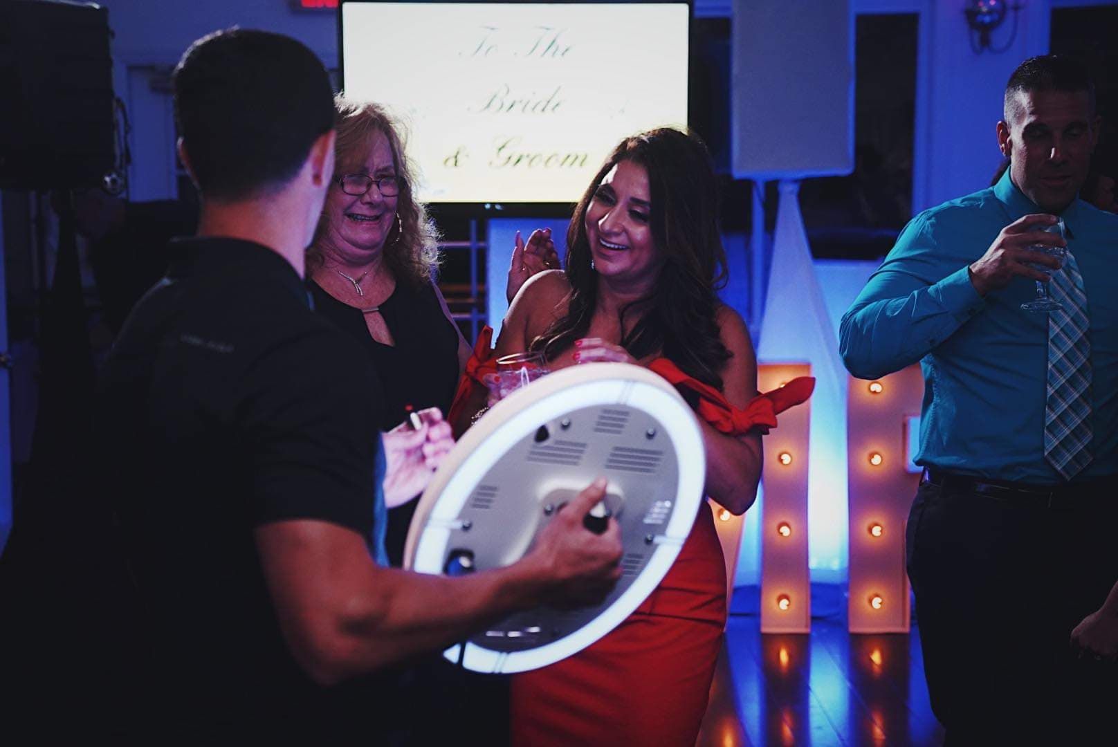 People interact with a handheld ring light at a celebratory event, with a 
