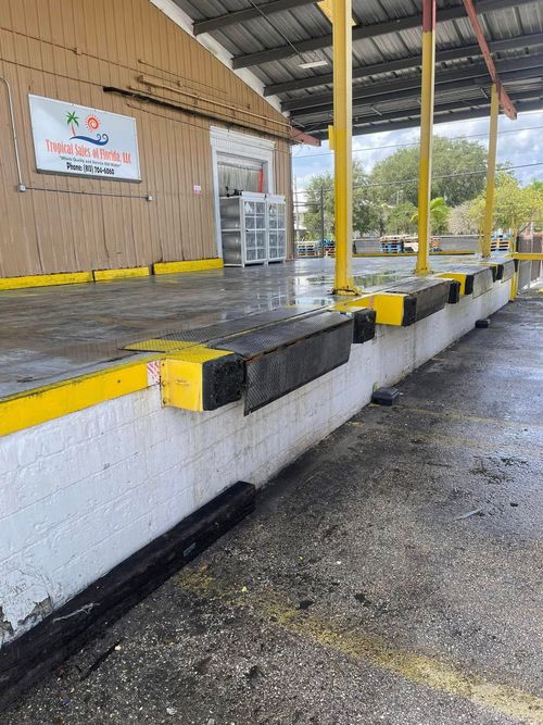 Empty drive-through lane beside a raised platform with yellow-and-black curb markers and wet pavement
