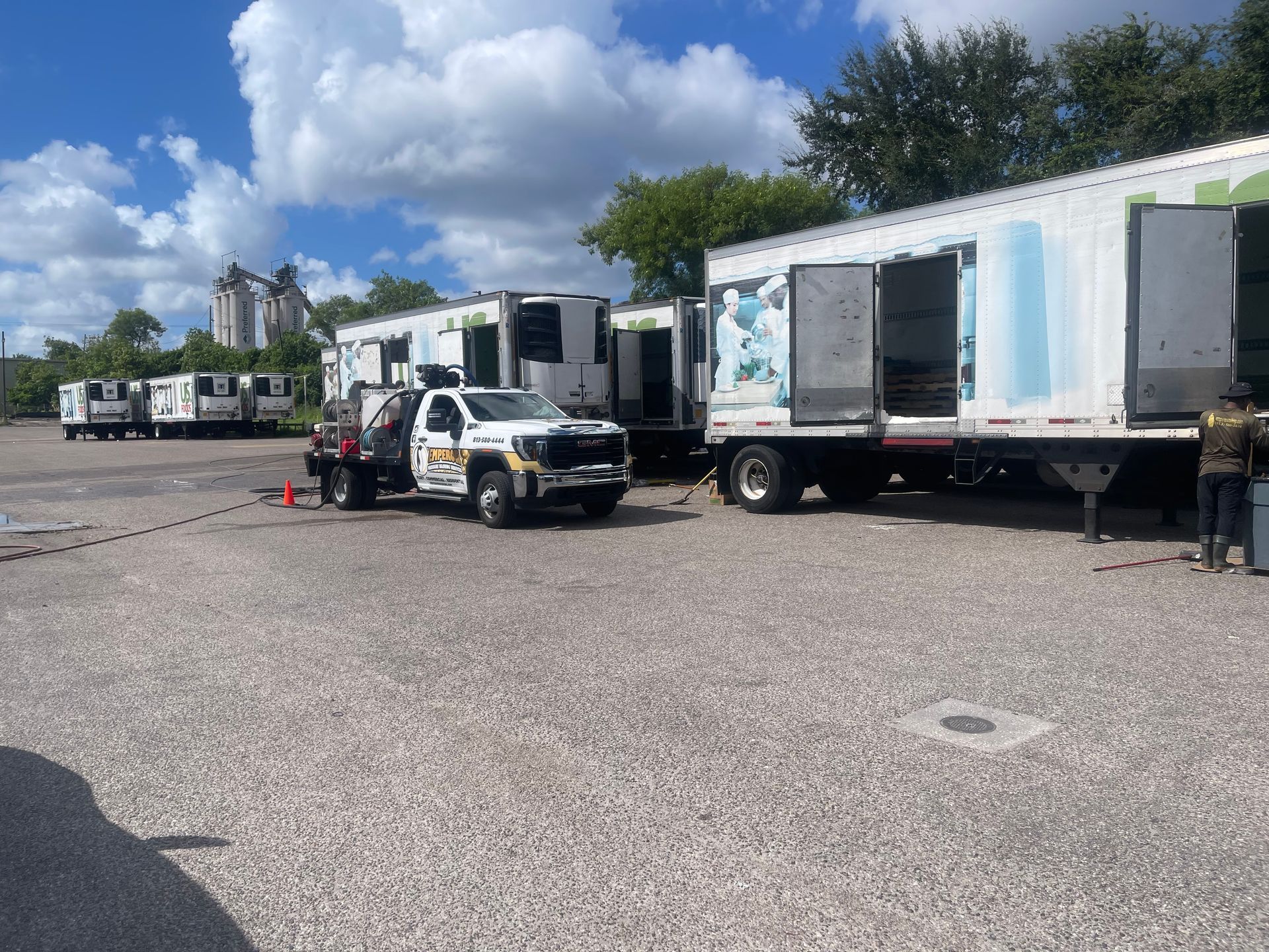 Truck yard with a white box truck and trailer parked on gravel under a blue sky