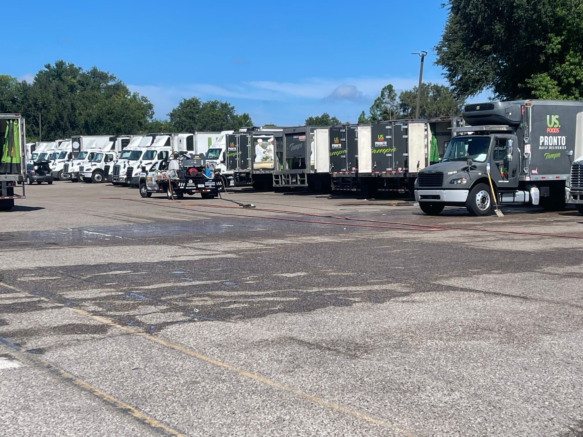Line of white trucks parked in a gravel lot under a clear blue sky