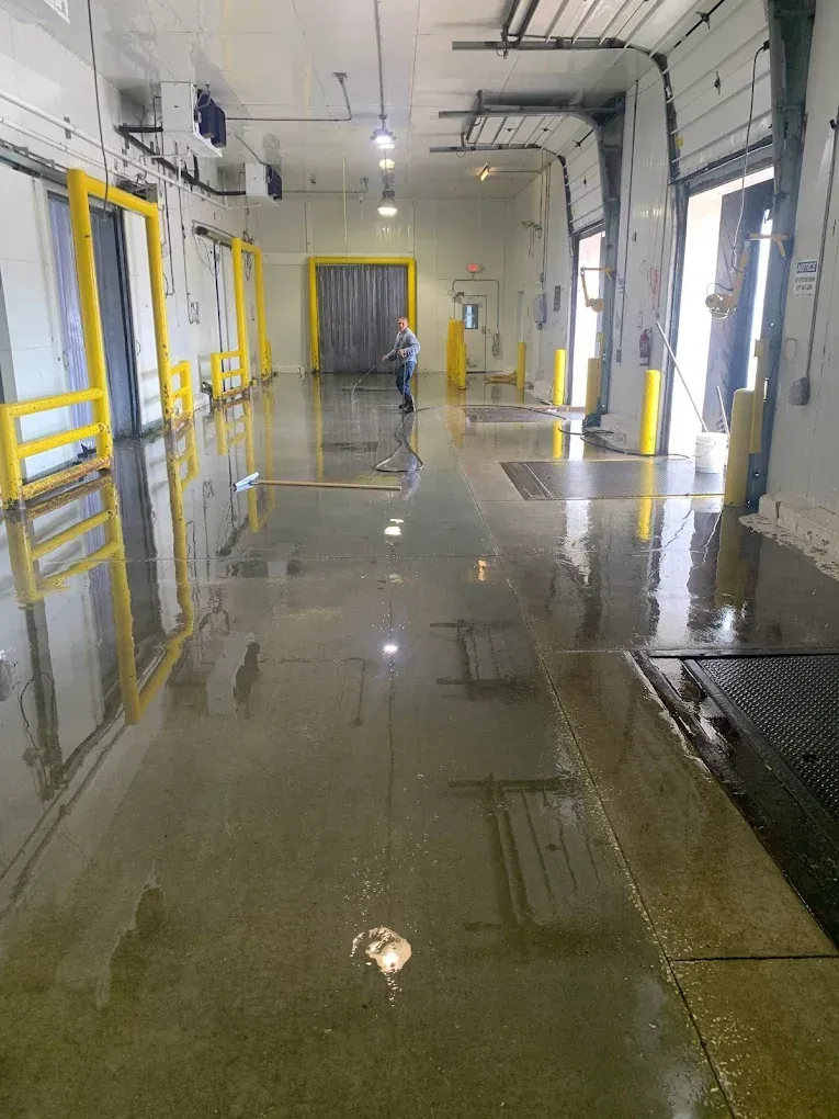 Wet industrial corridor with yellow railings and a person walking near the center.