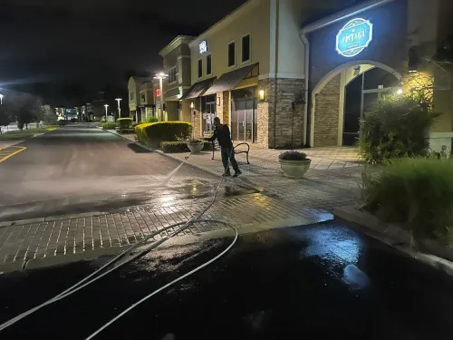 Wet night street outside a lit storefront, with a person standing near the entrance.