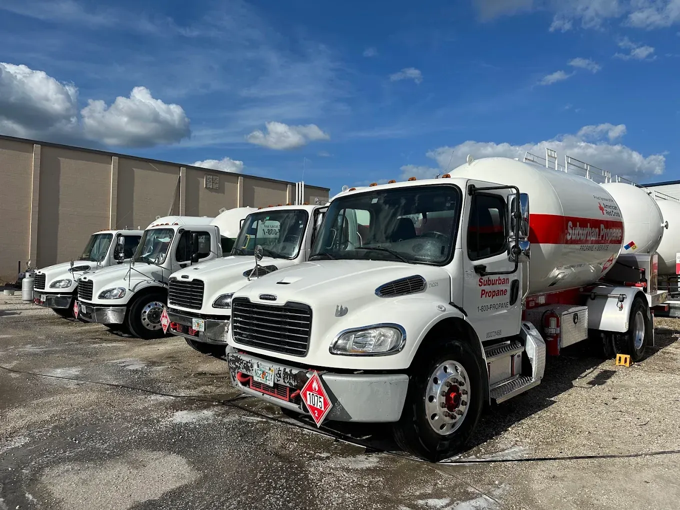 Three white cement mixer trucks parked in a lot under a blue sky
