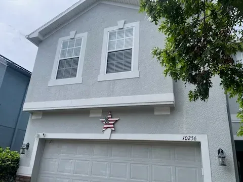 Gray two-story house with white trim, double garage, and a small American flag above the driveway.