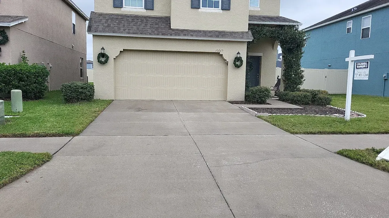 Suburban house exterior with a wide concrete driveway and two-car garage