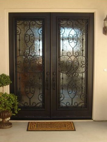 A pair of wrought iron doors with a rug on the ground in front of them.