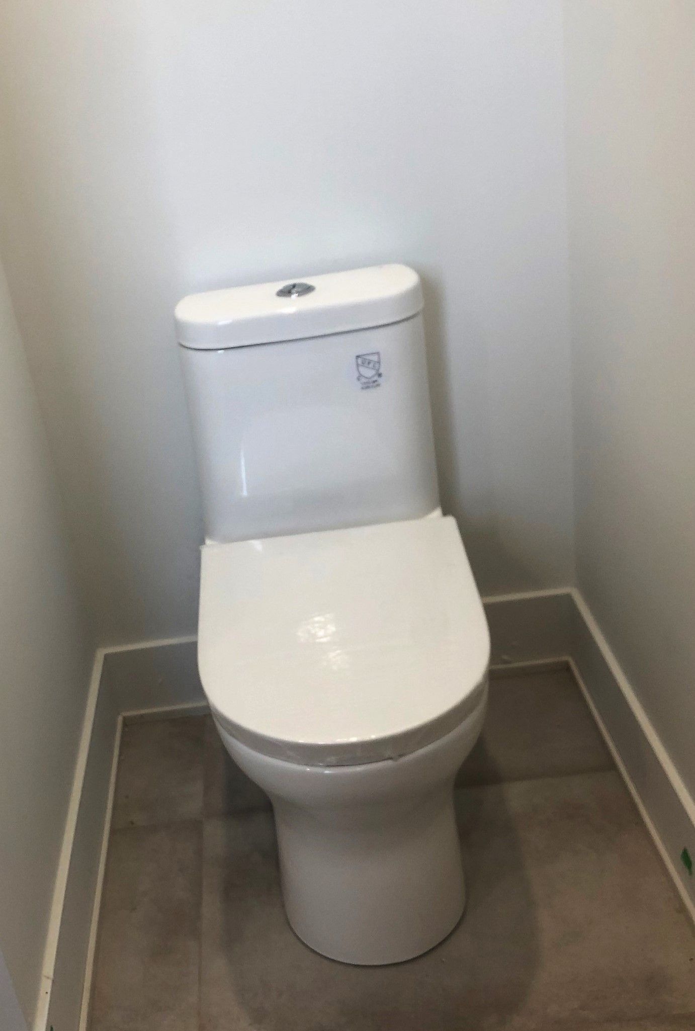 A white toilet is sitting on a tiled floor in a bathroom.