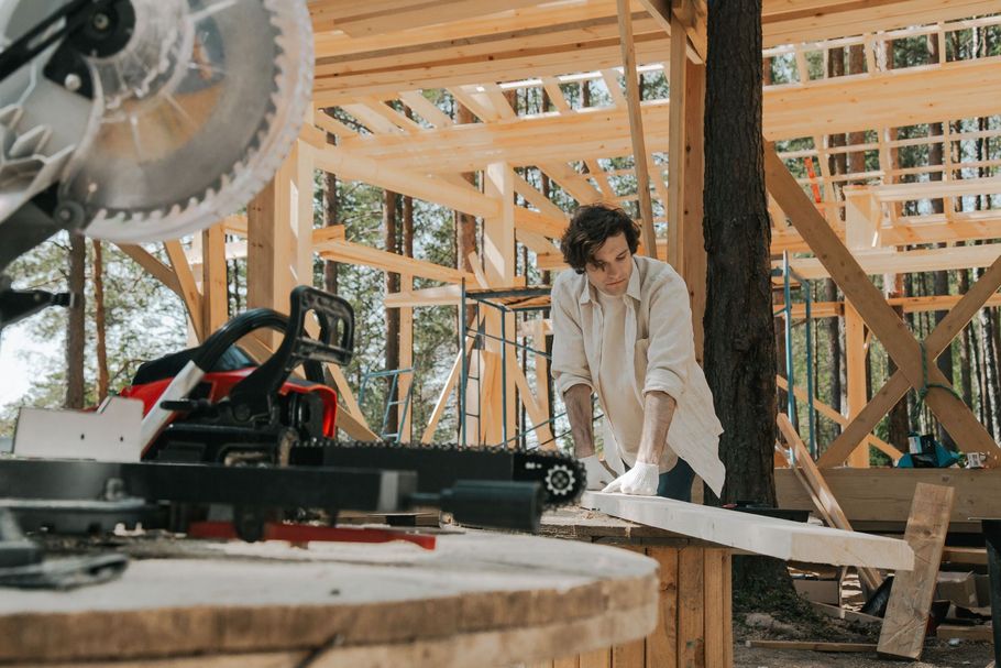 Person cutting wood with a circular saw in a framed house under construction