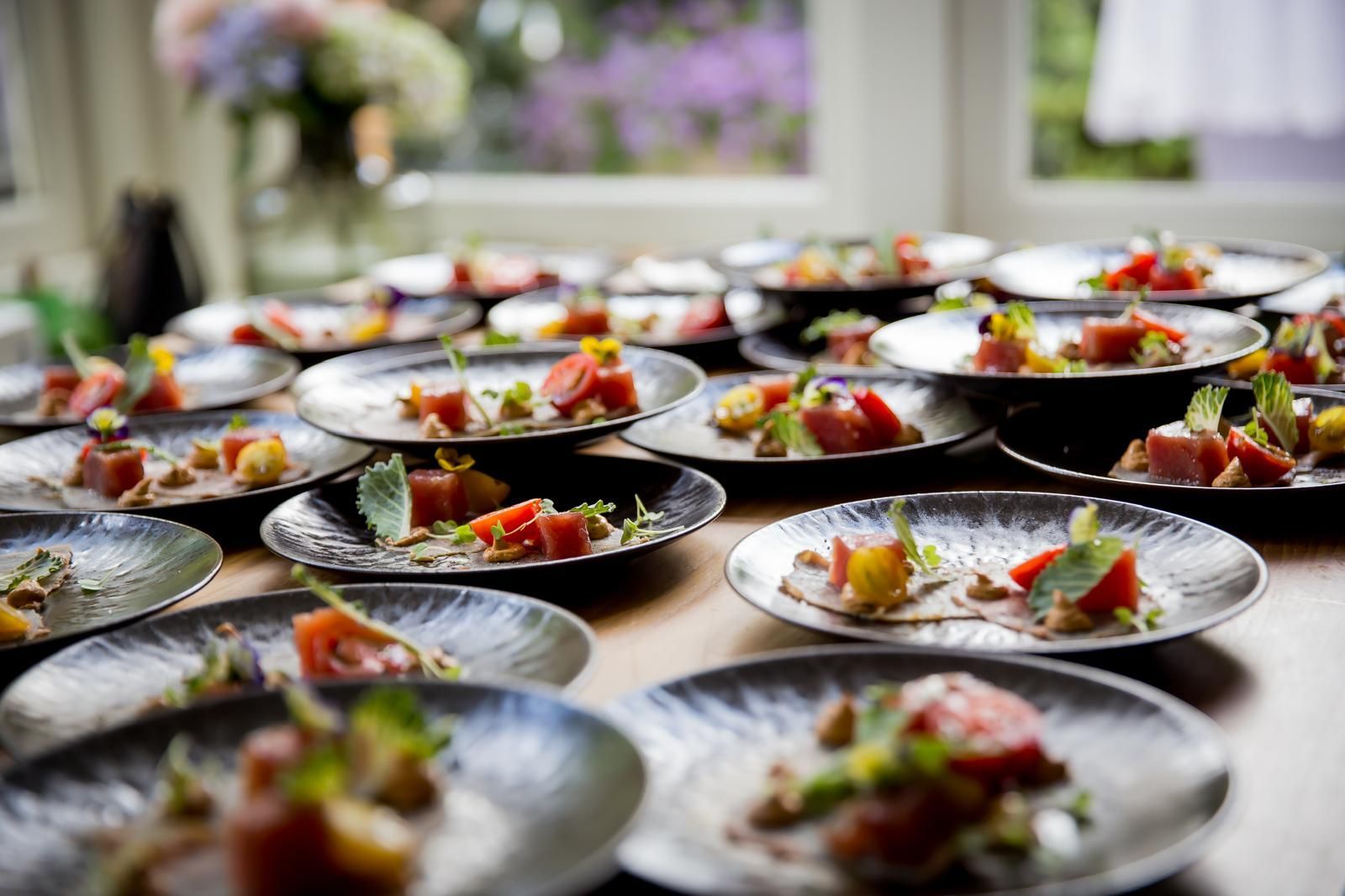 Borden met eten, elk met tomaat, kruiden en kleine groenten, staan ​​uitgestald op een tafel.