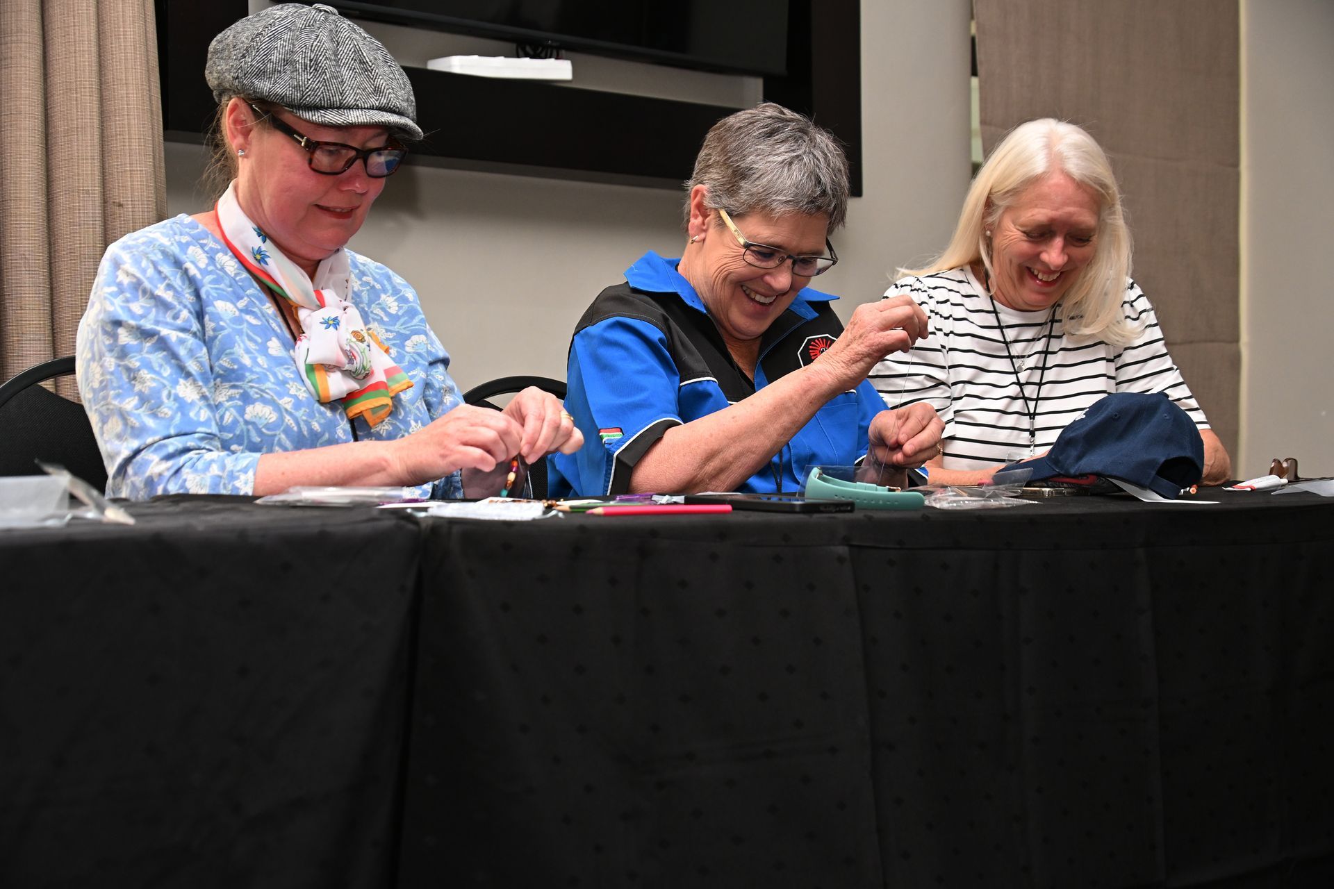 Three people seated at a table, smiling and working together at a craft activity.