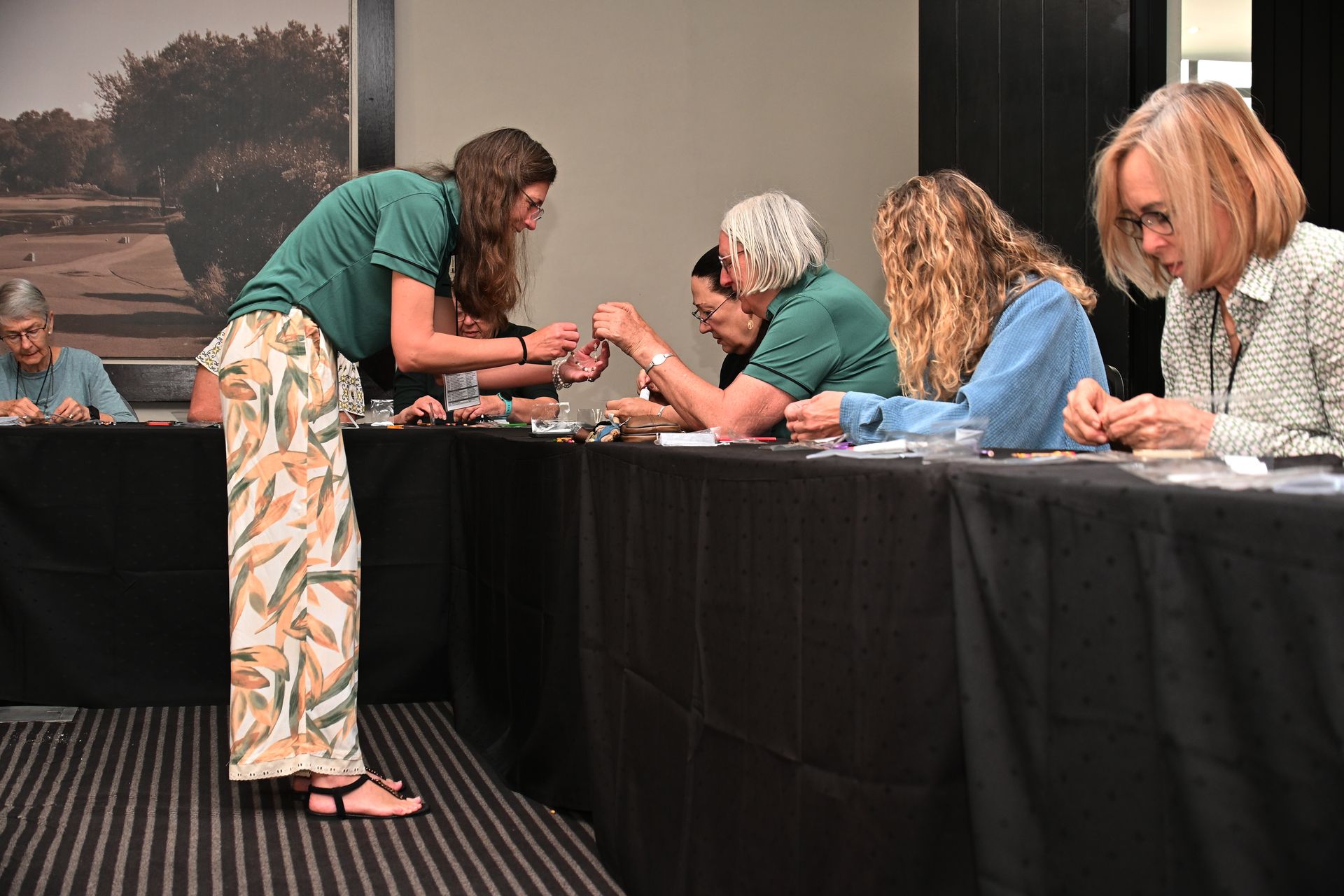 Person hands item to seated volunteer at registration table indoors