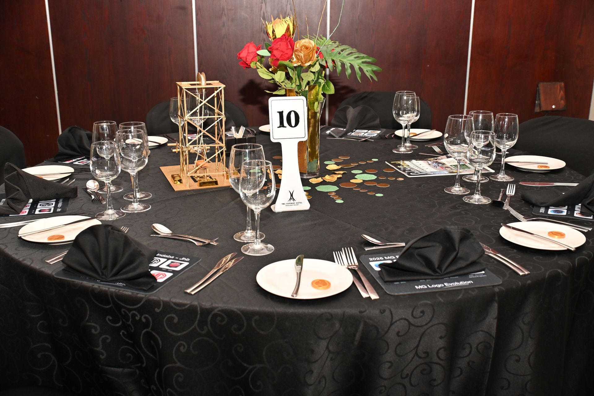 Elegant round banquet table set with black napkins, glassware, floral centerpiece, and table number 10