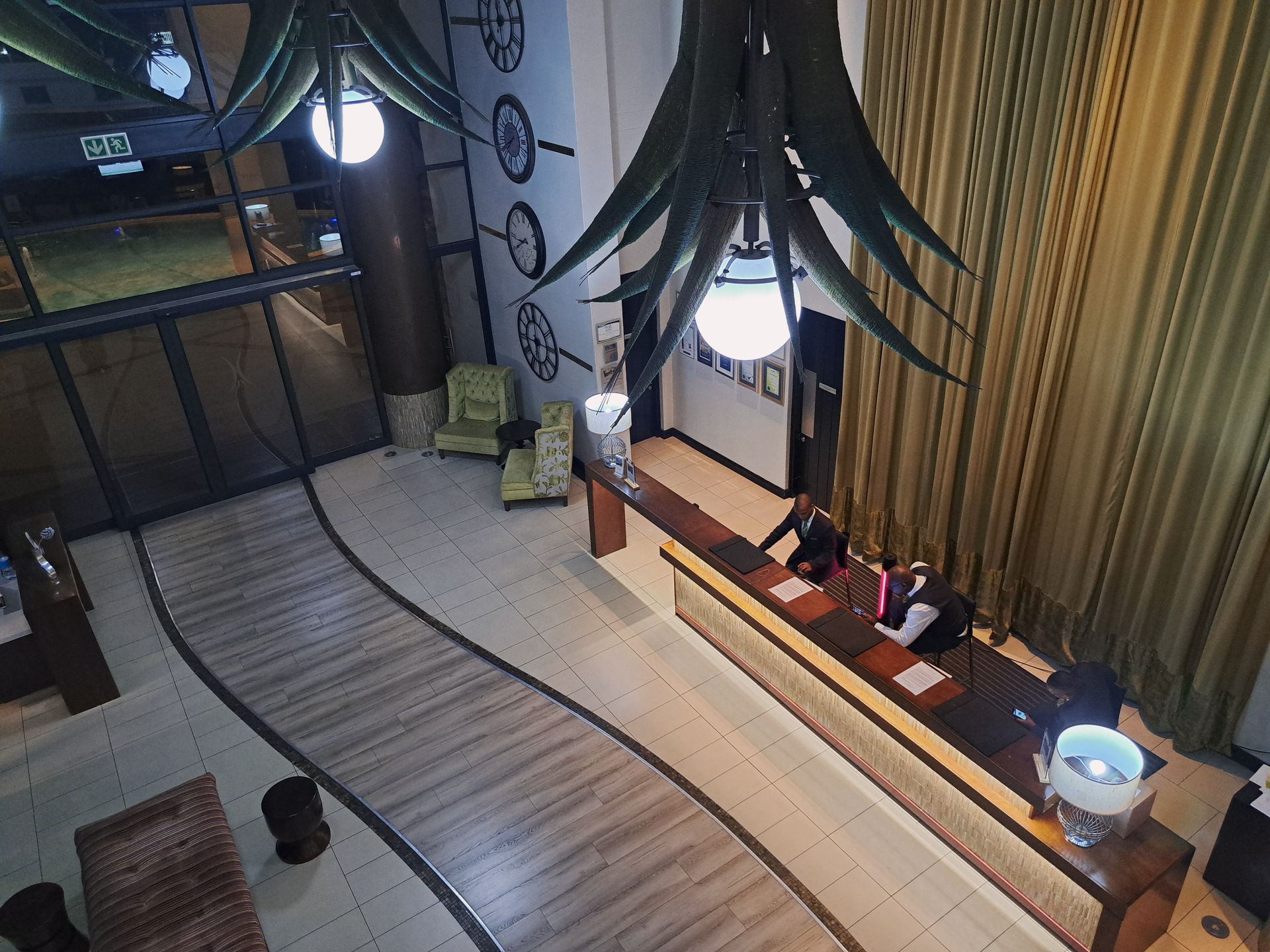 Modern room with a curved wood floor, hanging lights, long desk, and curtains; a cat sits on the floor.