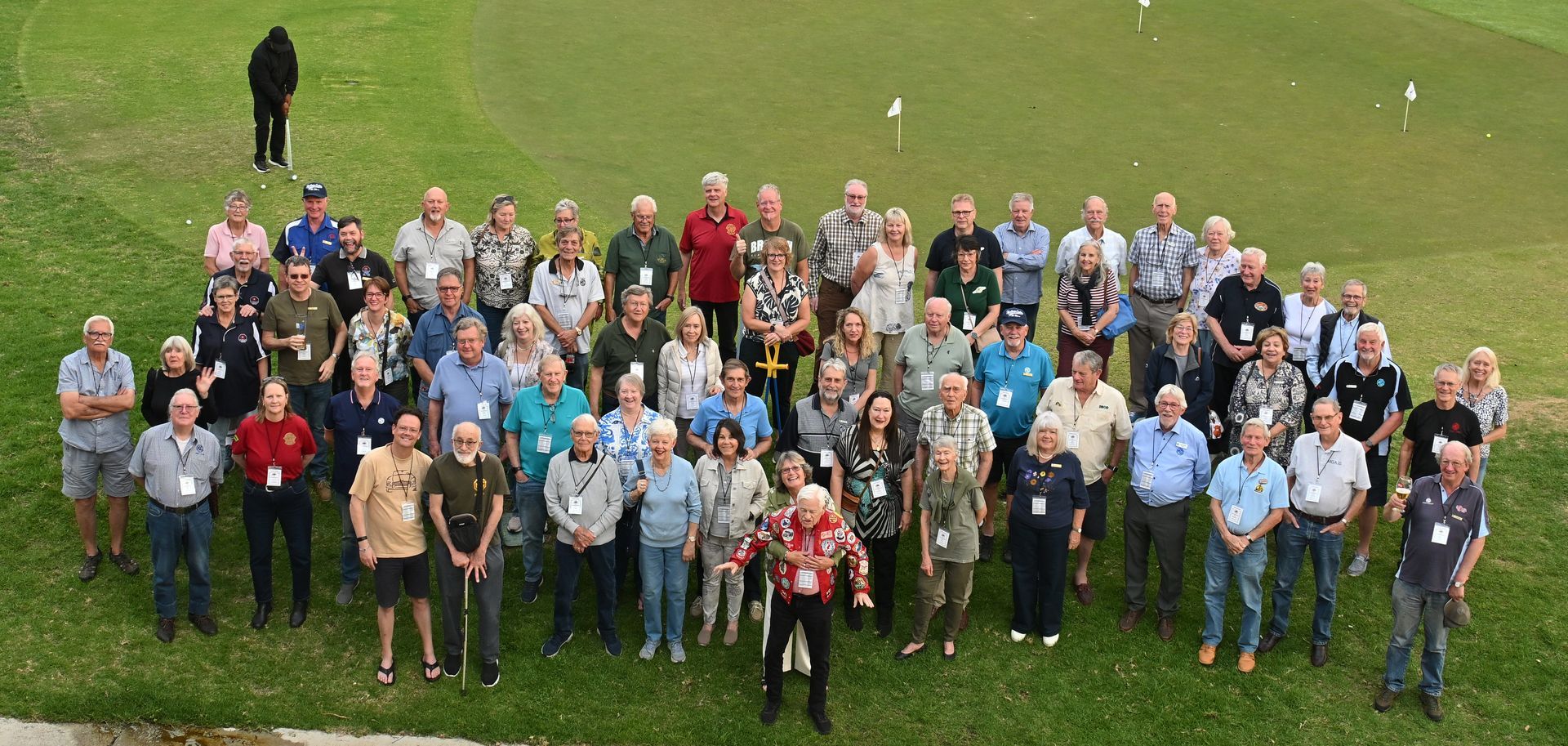 Large group of people standing together on a grassy field, posing for a group photo