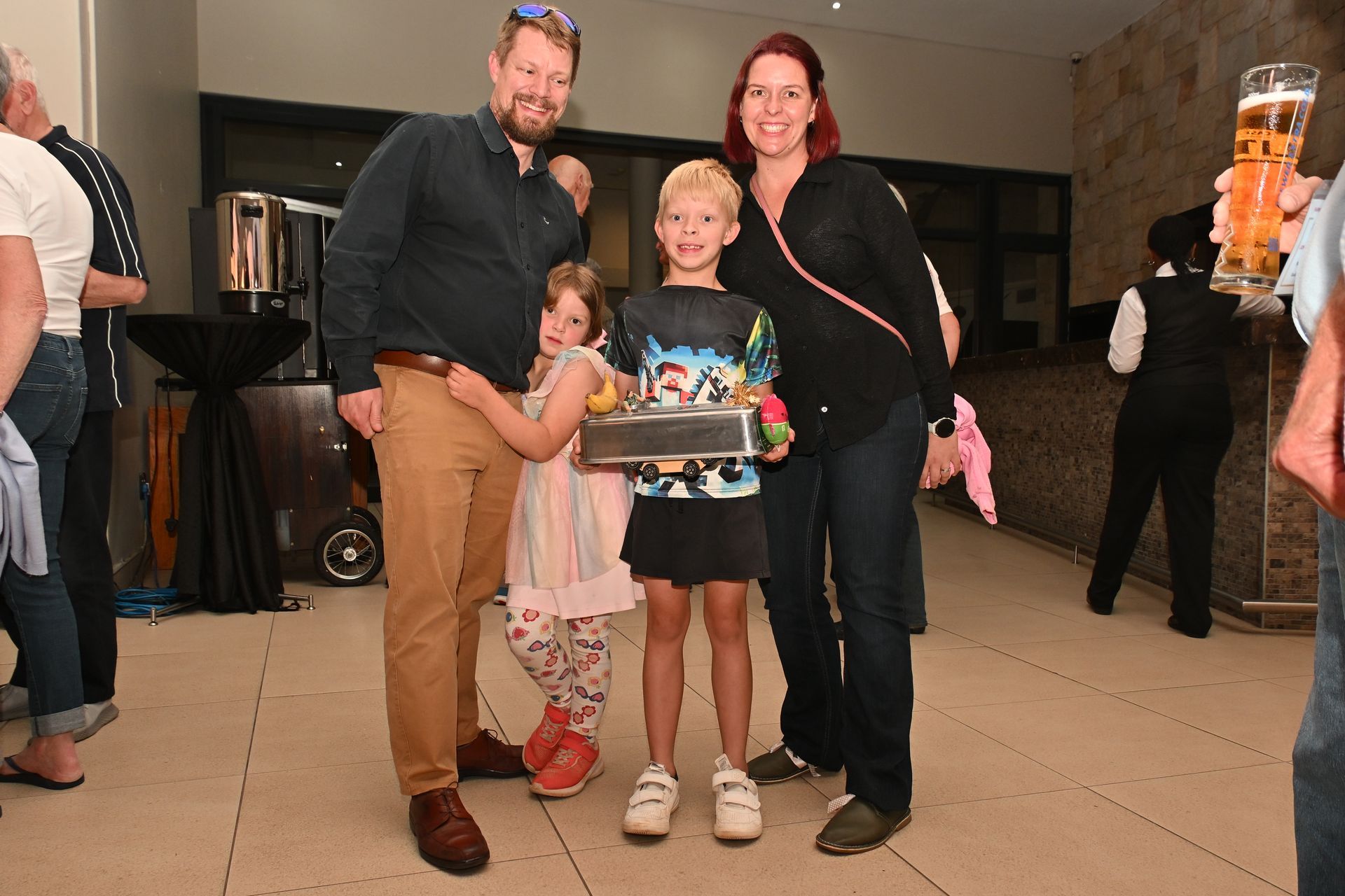 Group posing indoors, holding a basket and smiling at an event reception