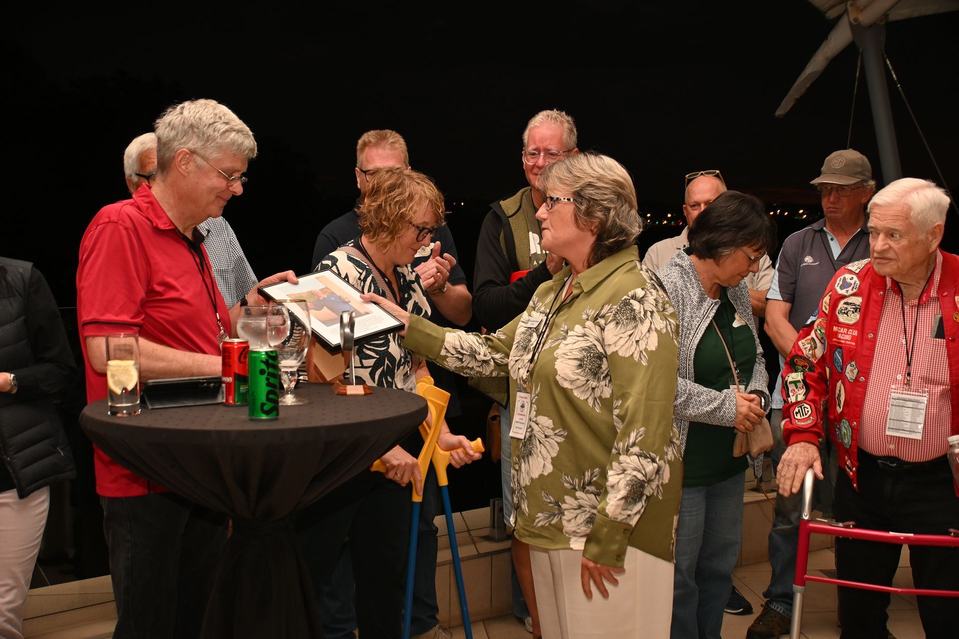 People gathered around a high table at a social event, chatting and holding drinks.