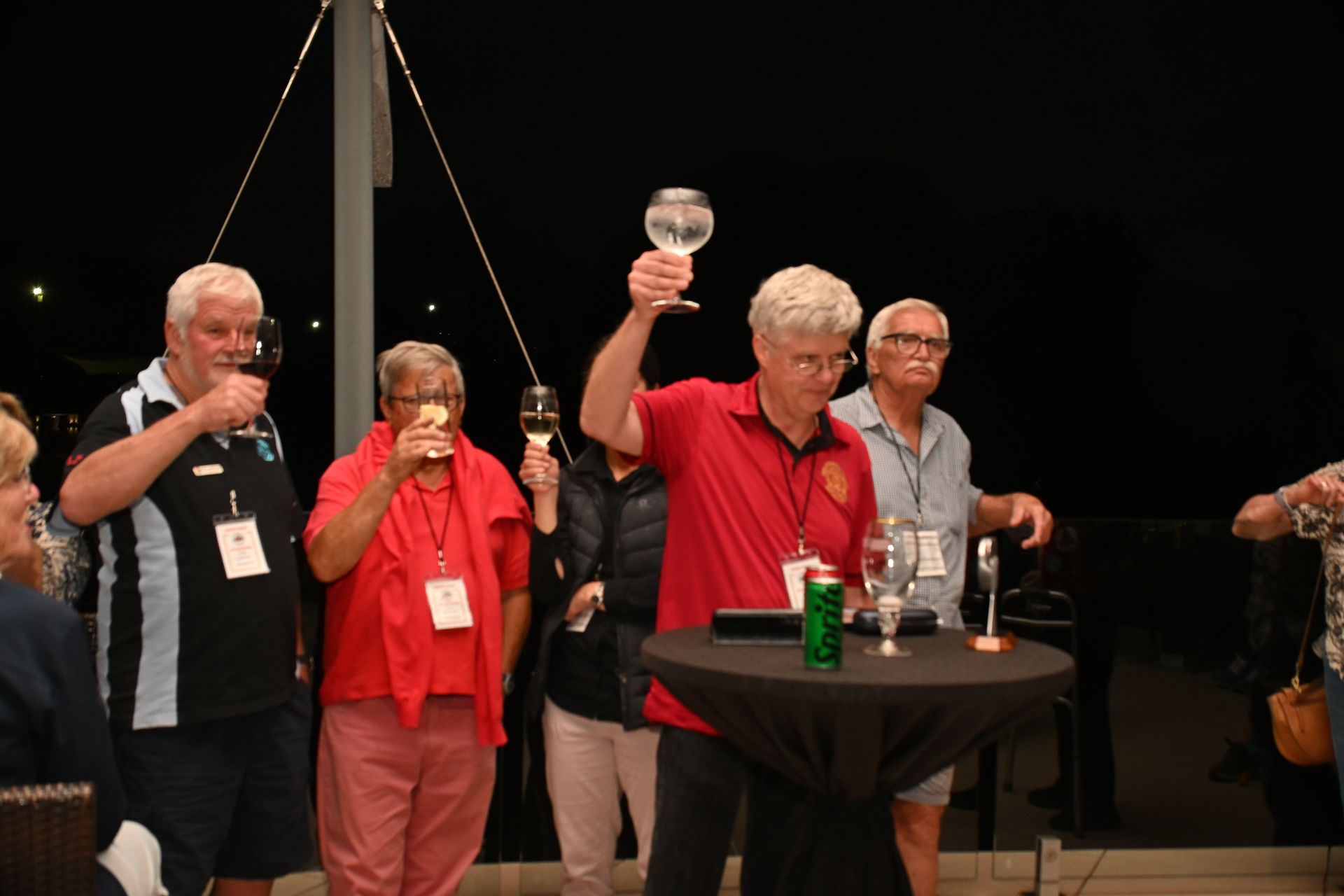 People raising glasses during a toast at a dimly lit indoor event