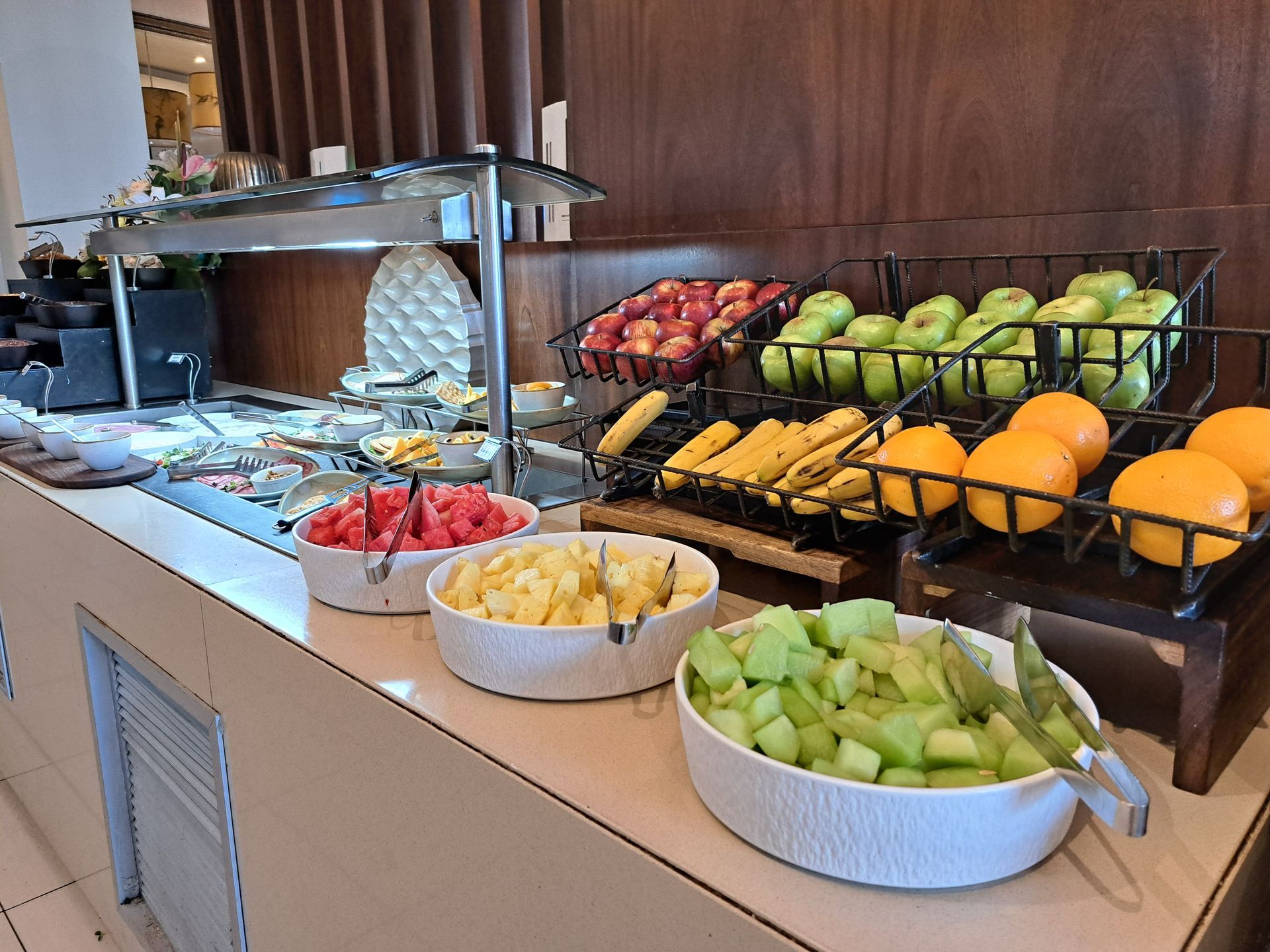 Breakfast buffet with fresh fruit bowls, melons, grapes, and strawberries on a countertop