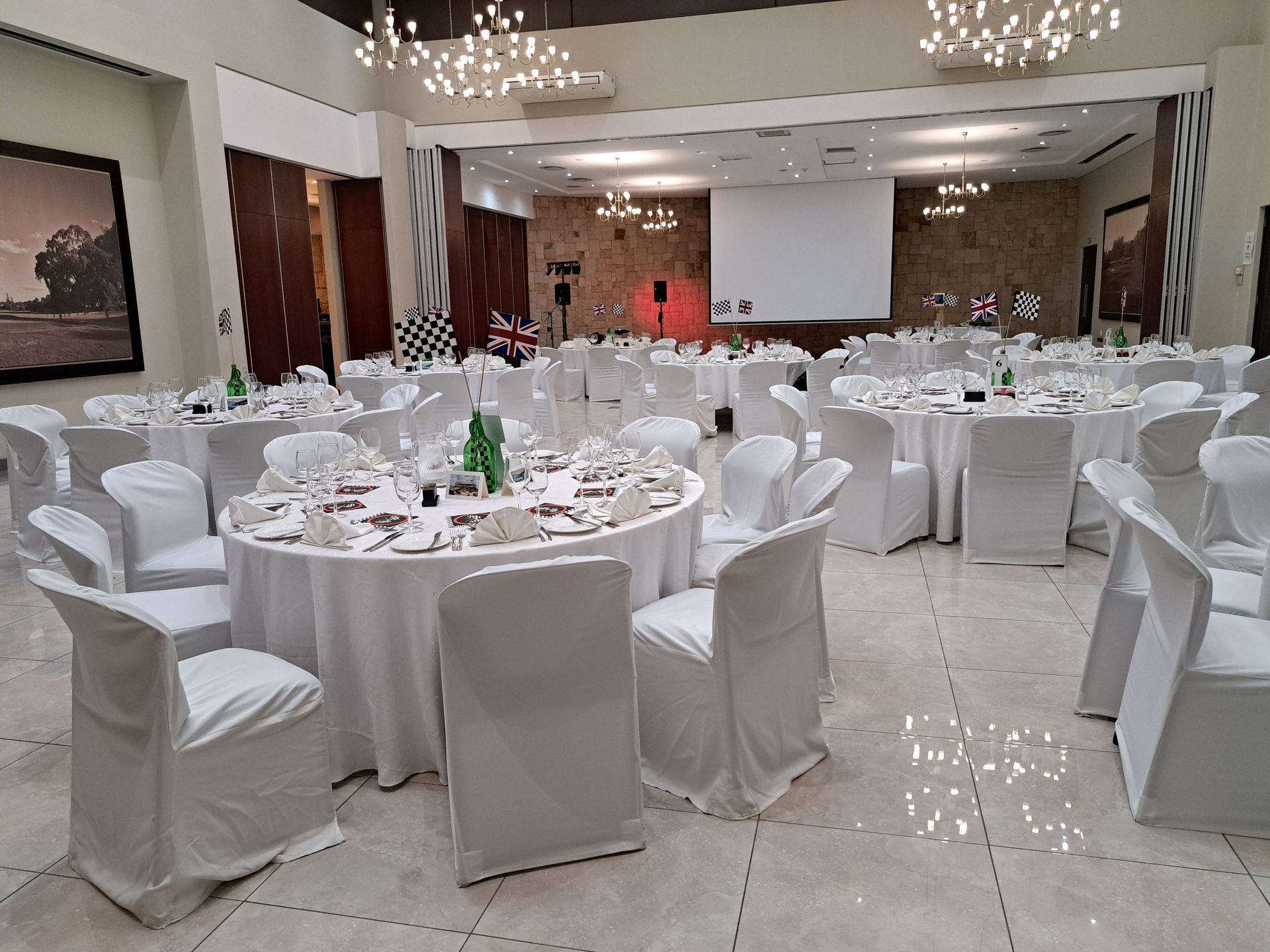 Elegant banquet hall with round tables and white chair covers, set for a formal event