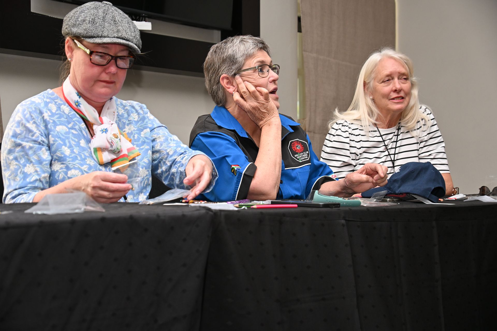 Three panelists seated behind a table, one speaking while the others listen attentively.