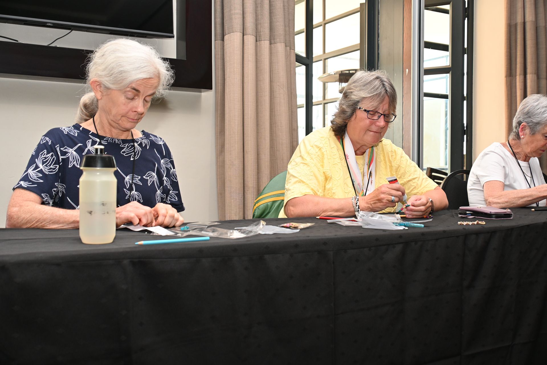Three people seated at a table, writing during a meeting or event.