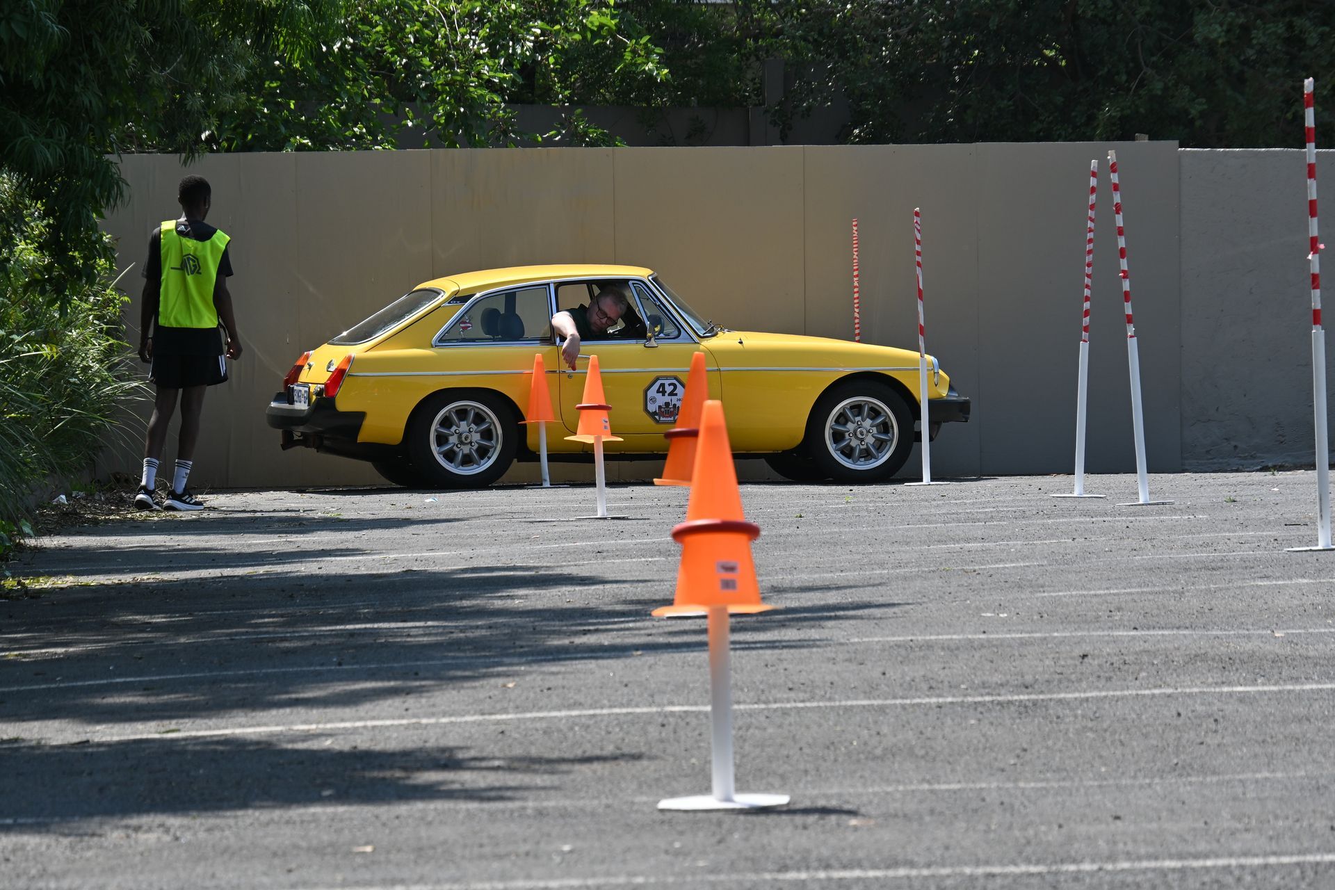 Yellow sports car parked on a cone-marked driving course with a person standing nearby