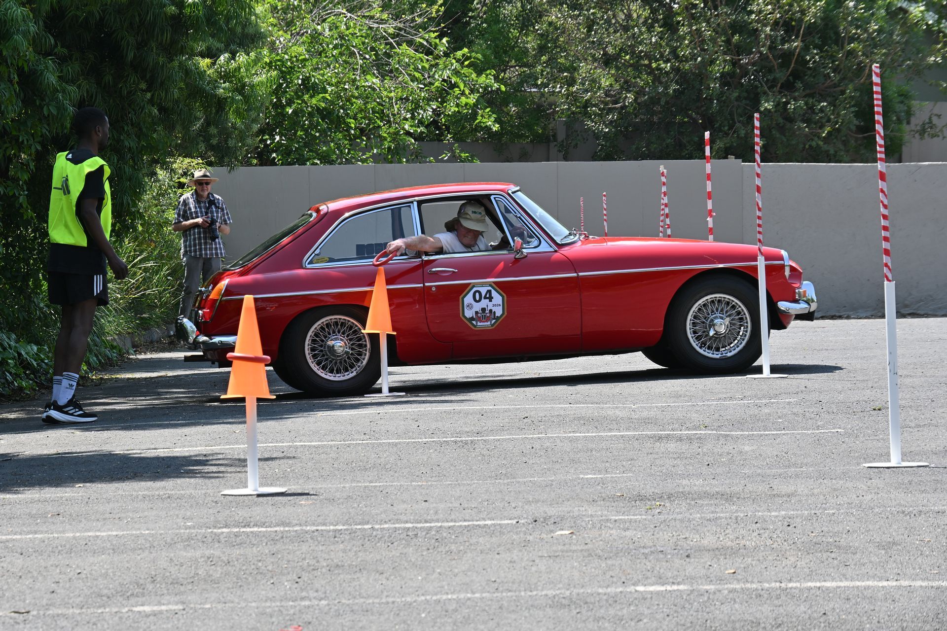 Red vintage sports car on a driving course with cones and a marshal nearby