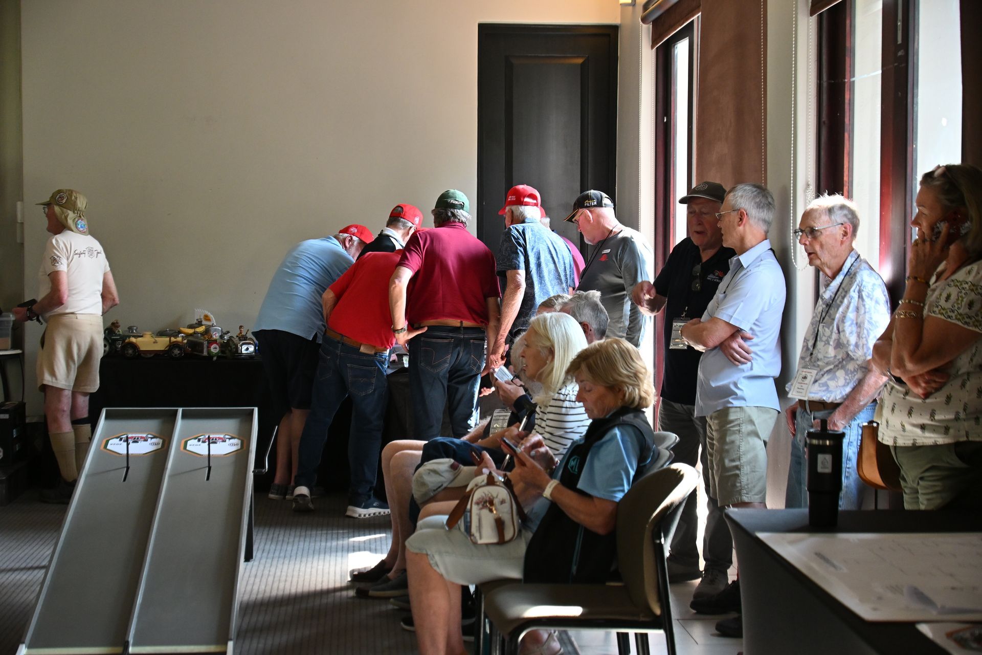 People gathered in a bright indoor room, leaning over a long counter and waiting in line
