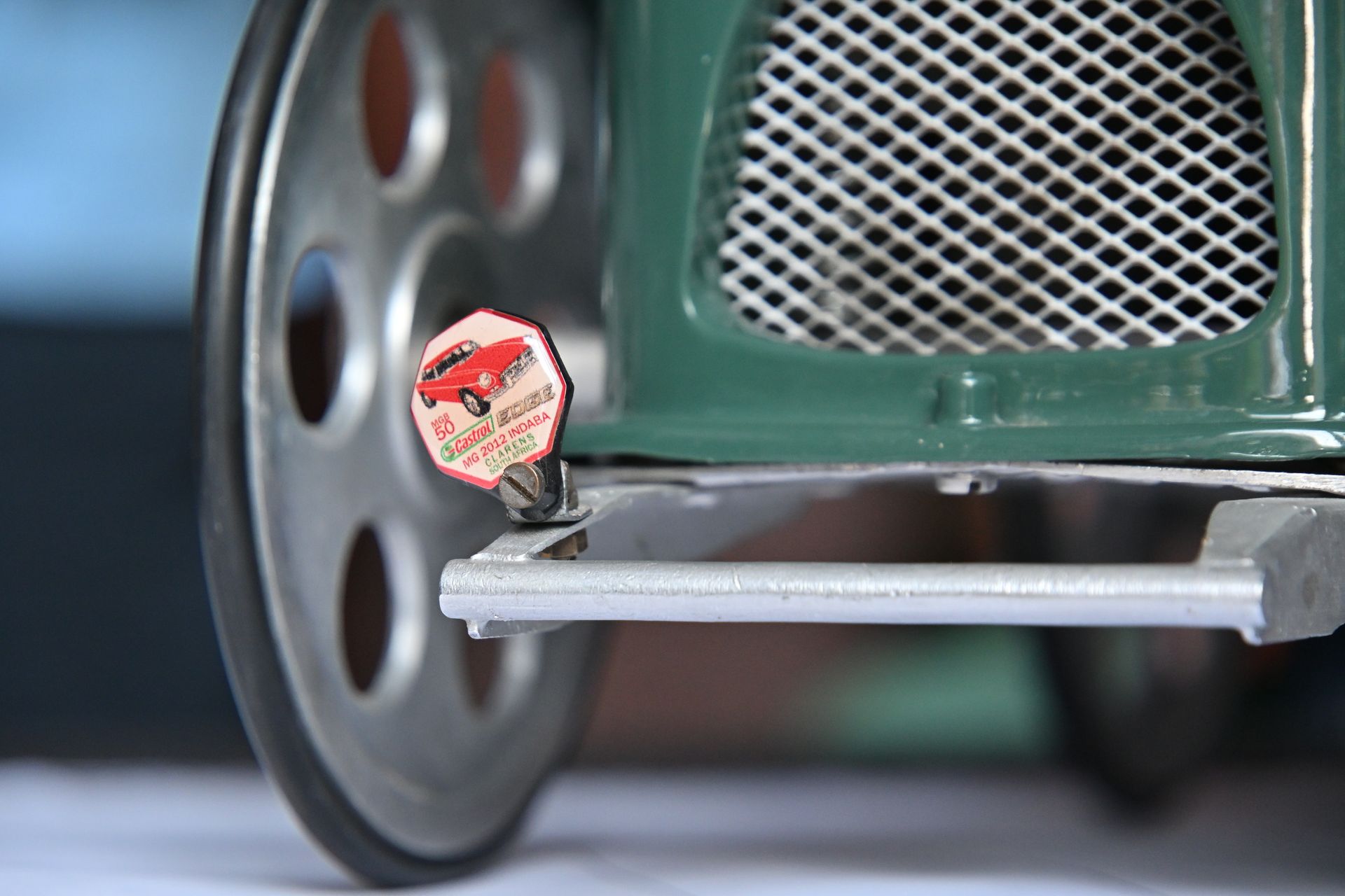 Close-up of a green stroller wheel with a small toy attached to the front bar
