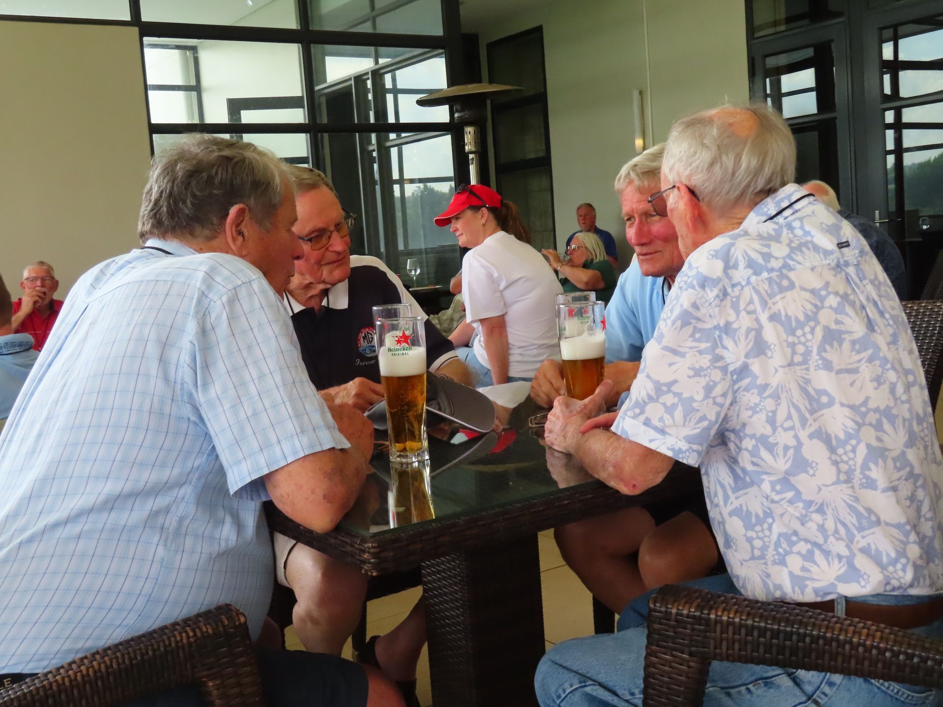 People seated around a table chatting in a bright indoor café or patio.