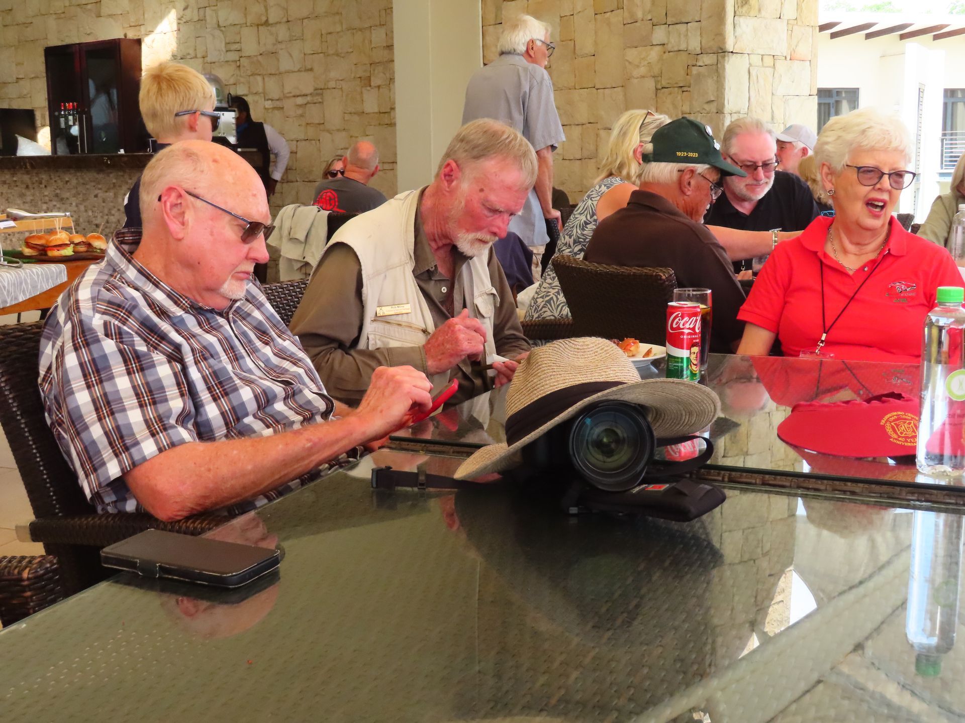 People seated around a patio table, looking at a phone in a casual outdoor dining area.