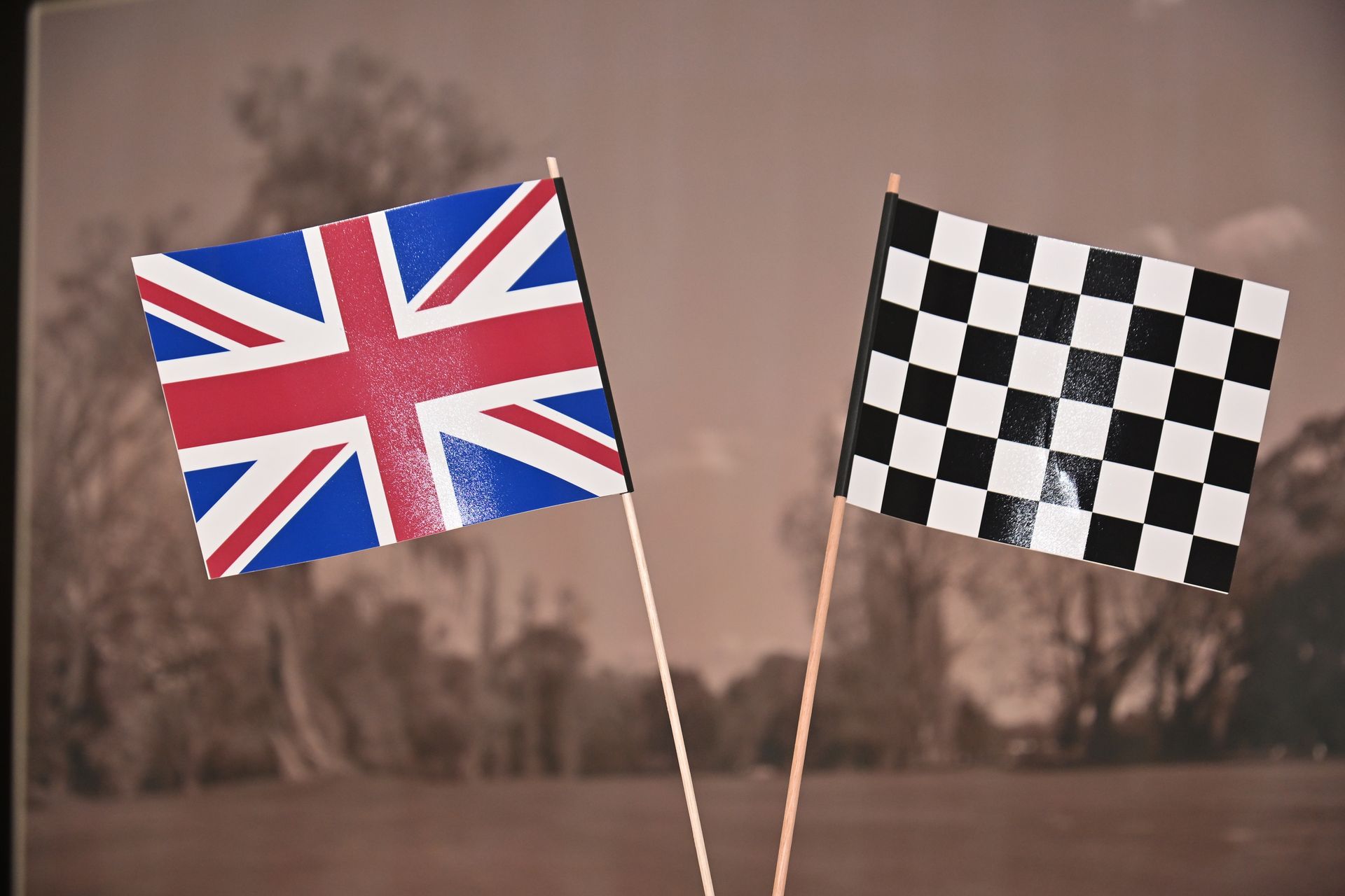 British Union Jack and checkered racing flags on poles against a blurred outdoor background